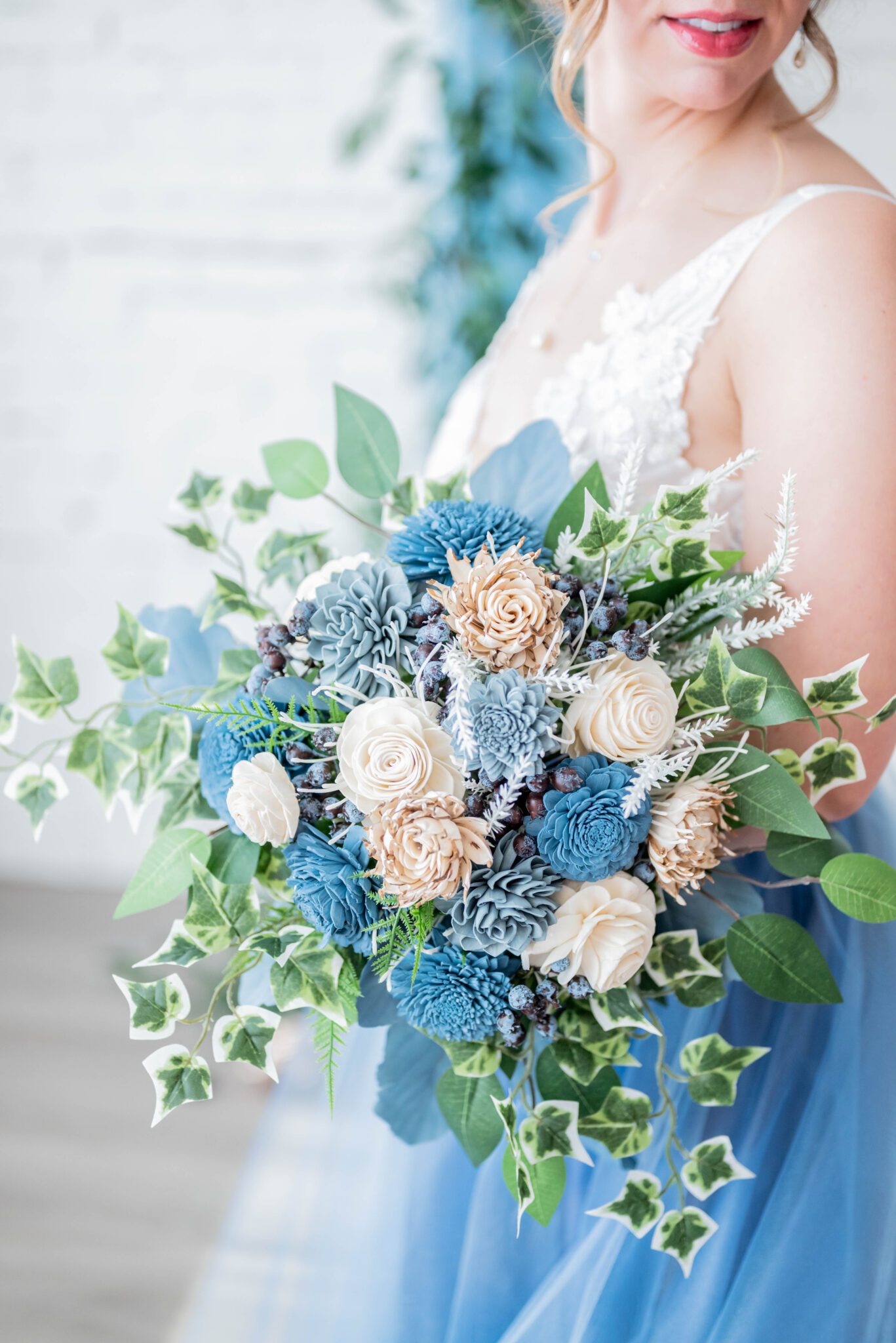 Lush bouquet with baby blue, teal and peach florals framed with greenery by Prairie Chic Designs in bridal portrait, french-inspired wedding decor with baby blue accents, traditional wedding style with a modern twist