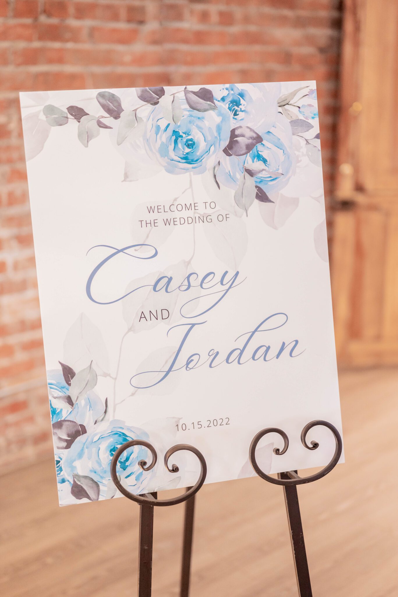 romantic welcome sign with baby blue roses, grey-toned vines and calligraphy sits in a vintage easel, timeless elegance with a traditional wedding style, welcome sign ideas