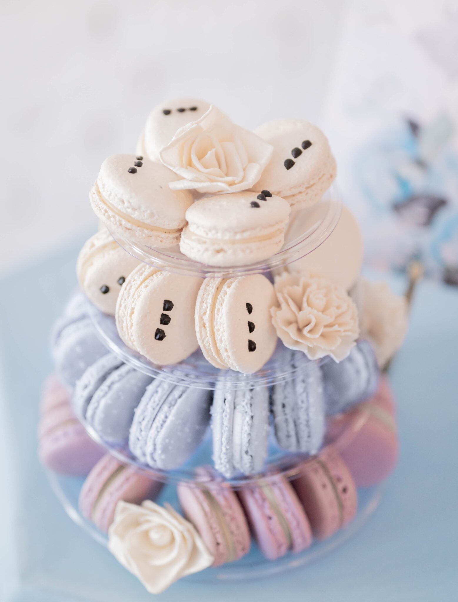 Tiered display of macarons in purple, baby blue and creamy white decorated with white florals, french macarons are a unique wedding cake alternative, purple and baby blue colour palette ideas