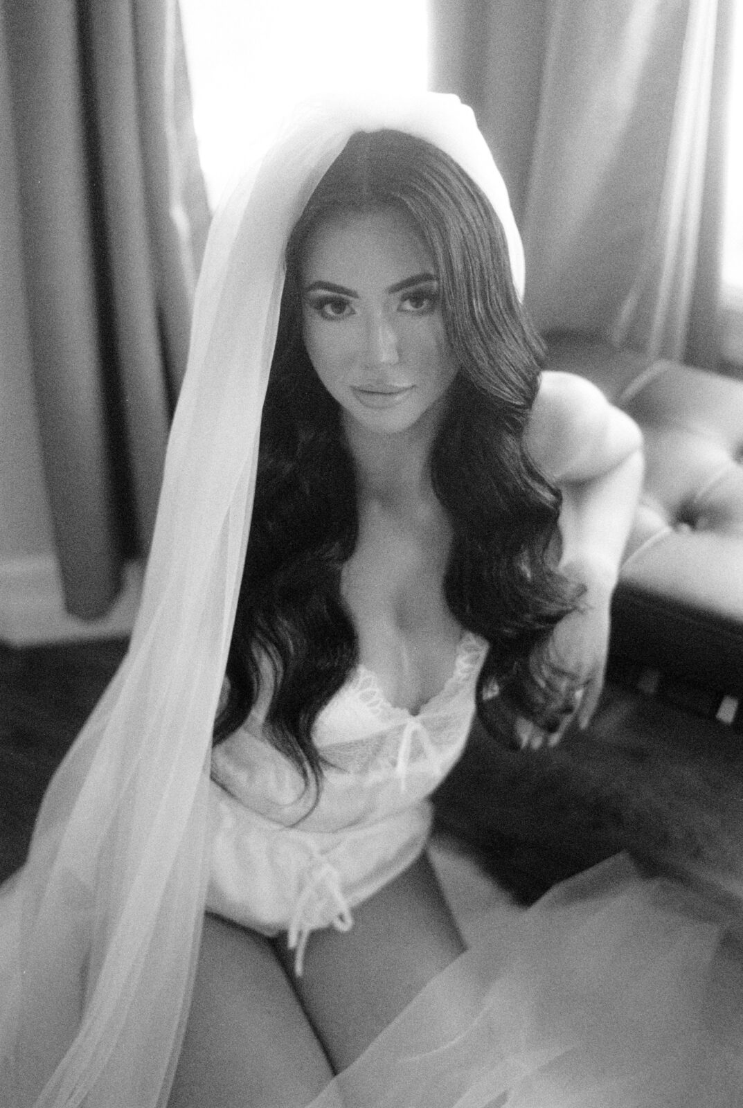 Seductive elegance in black and white bridal boudoir portraits, Bride posing in white lingerie and veil for intimate bridal photoshoot