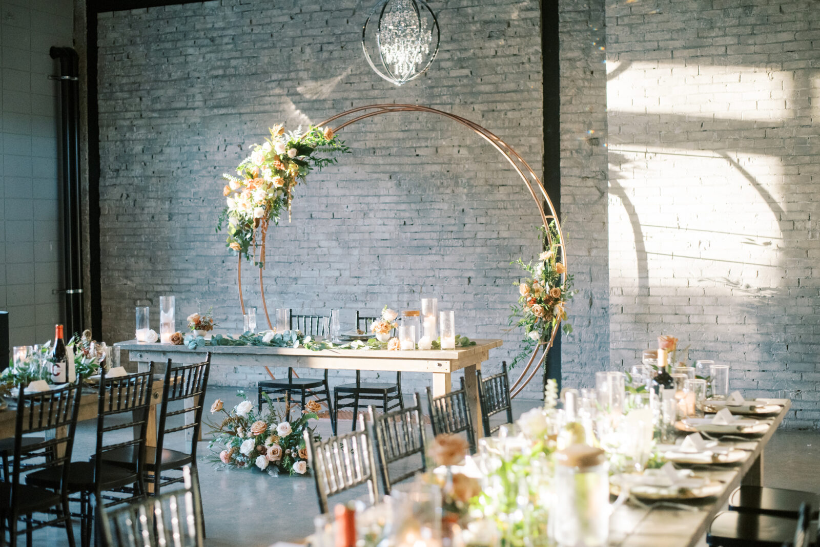 Golden hour photos of wedding reception in industrial venue in Edmonton, Alberta, gold arch back drop behind sweetheart table with pockets of fall-toned florals
