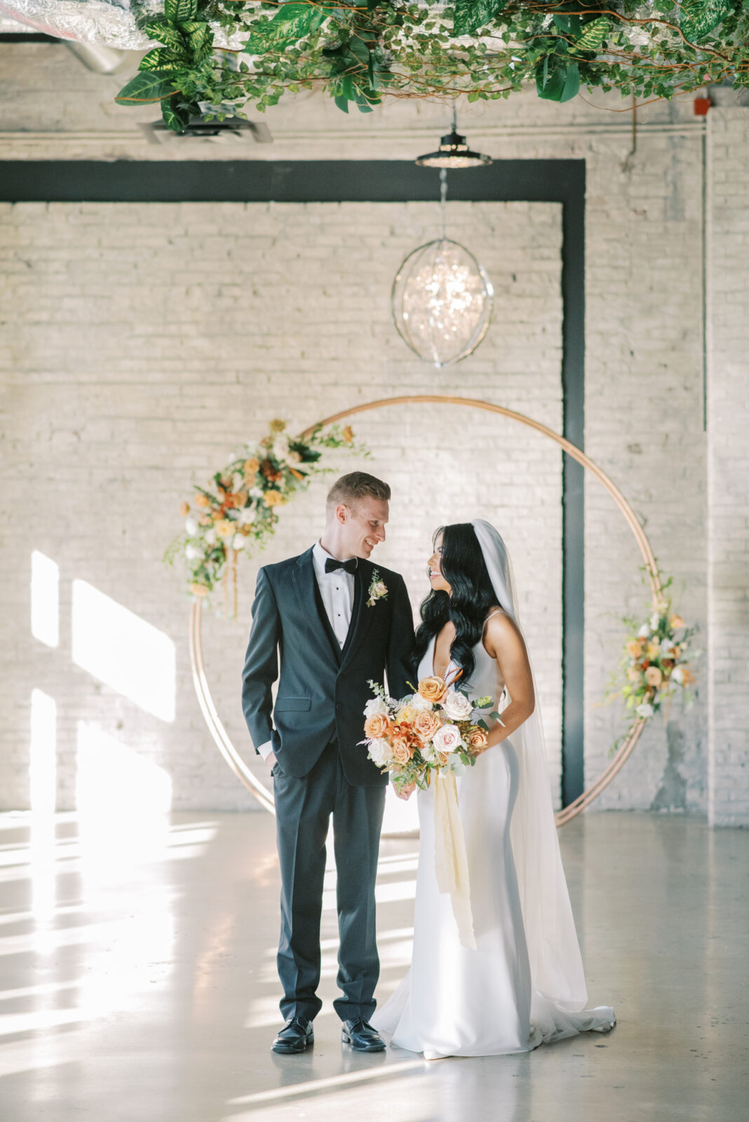 Bride and groom portraits in industrial wedding venue, unique circular arch design inspiration, fall-colour palette