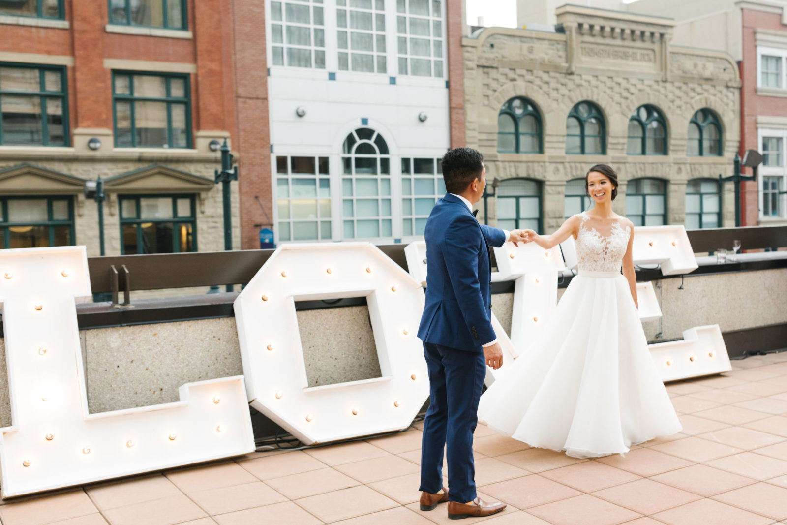 Bride and groom dancing infront of large love sign, captured by Shannon Yau Photography