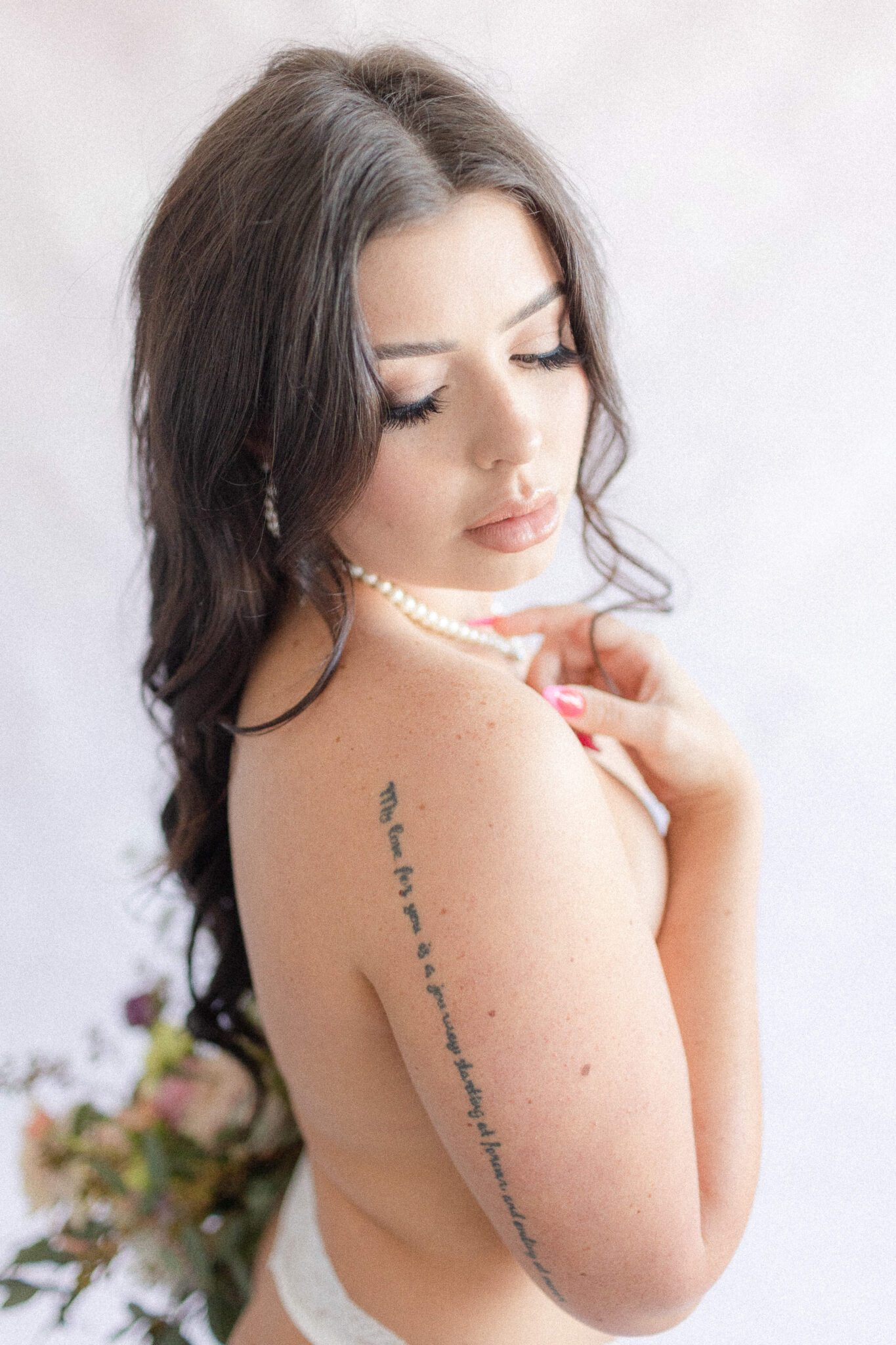 Bride-to-be posing for boudoir portrait wearing vintage pearls, holding gorgeous spring inspired florals. 