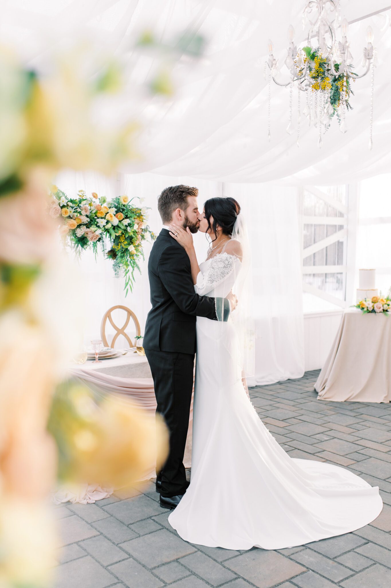 Couple kissing at stunning tented wedding, featuring yellow and peach spring wedding colour palette.