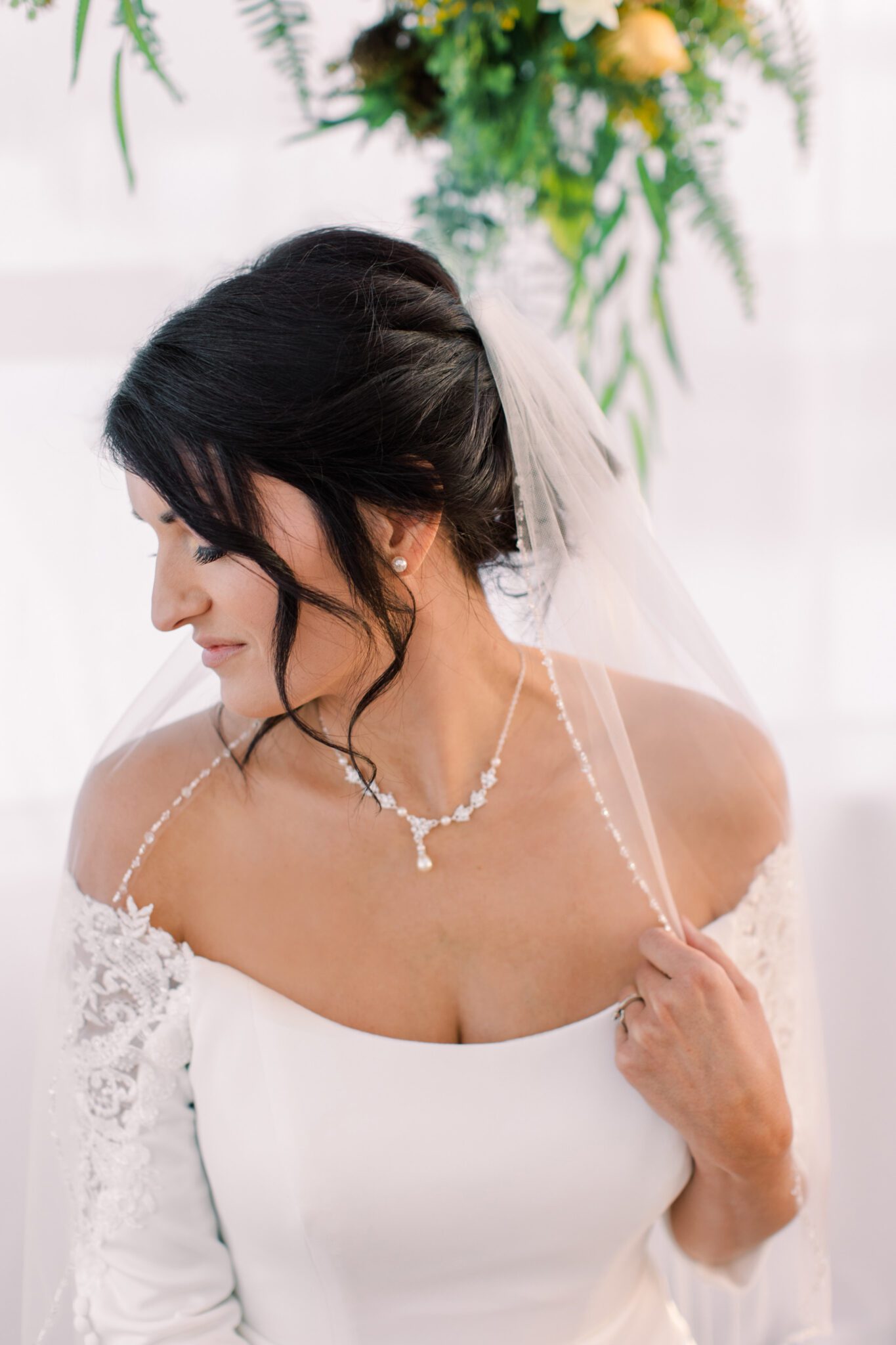 Bride wearing elegant off-the-shoulder gown featuring lace sleeve details, bridal hair and makeup by Desire at The Headroom 