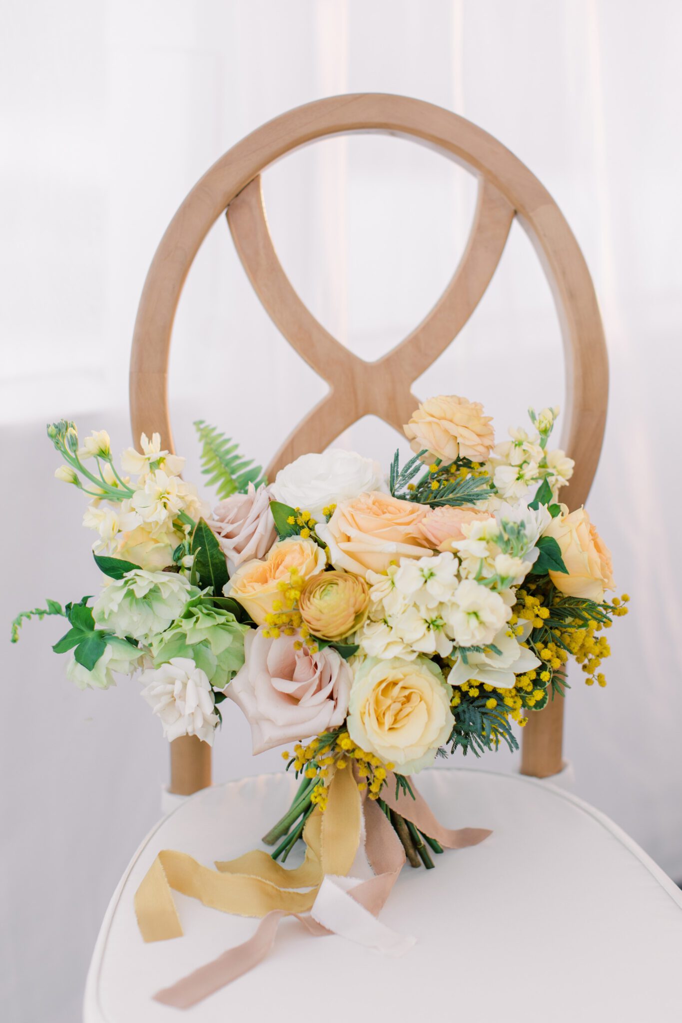 Spring inspired yellow, pink and peach wedding bouquet including  roses, ranunculus, and ferns designed by Little Petal Company
