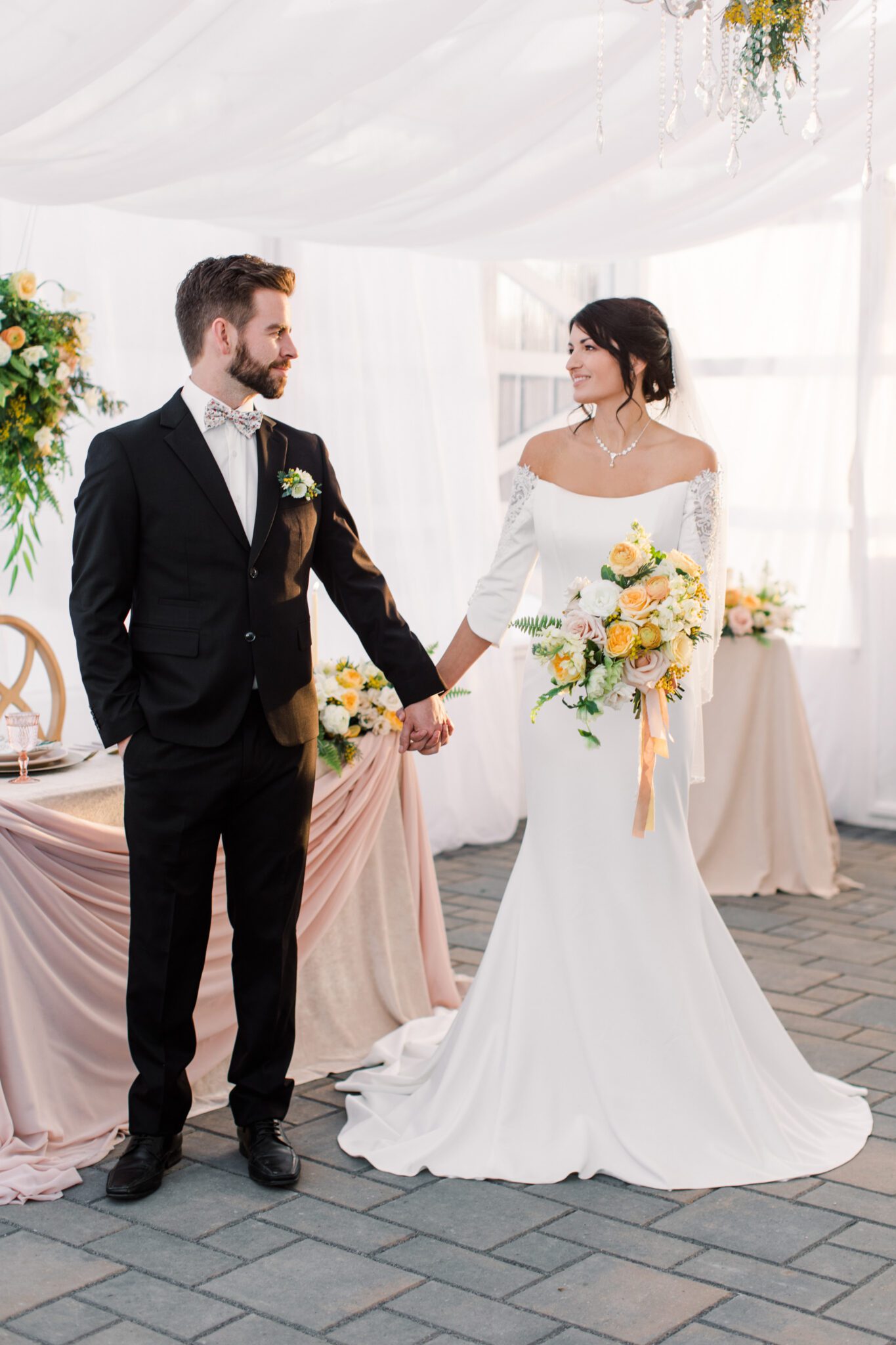 Bride and groom holding hands in tented wedding reception in Sunflower & Swallow's elegant, modern greenhouse located in Bezanson, Alberta