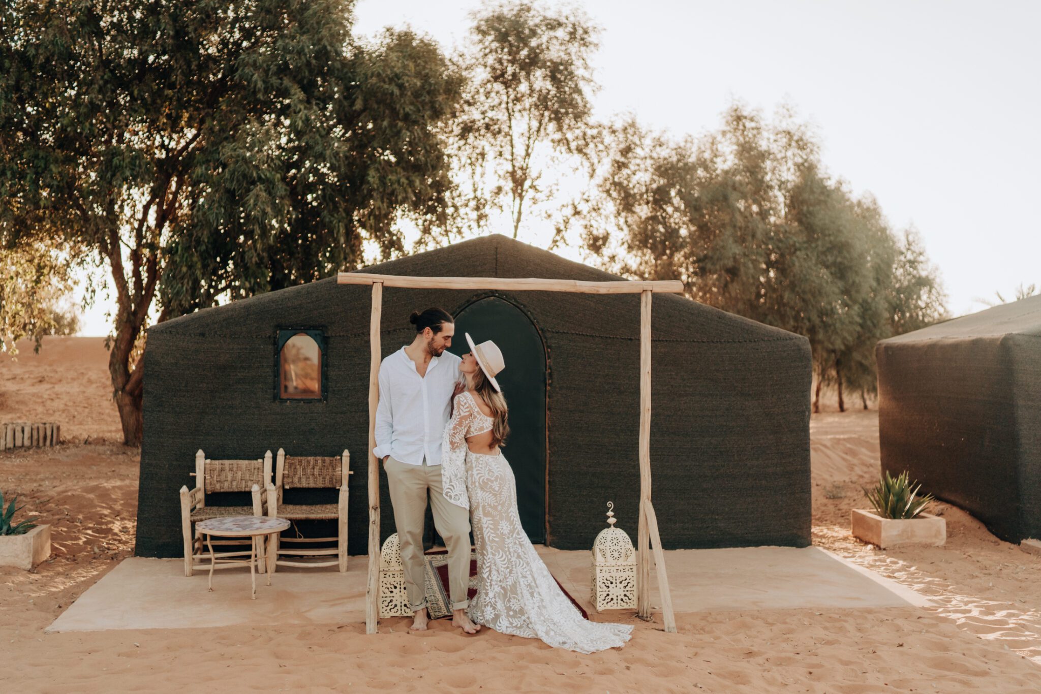 Couple standing in front of tent at Madu Luxury Camp during their golden sunrise engagement session.