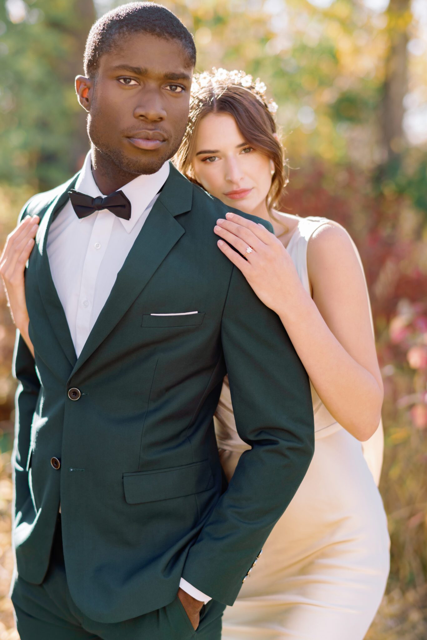 Couple embracing at intimate Fall wedding, groom wearing emerald green suit, and bride in elegant satin gown. 