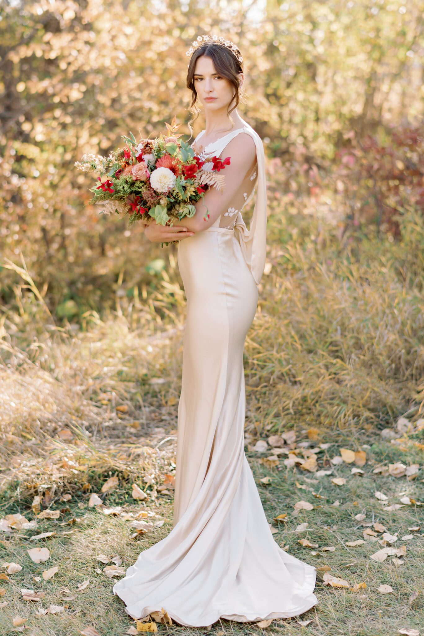 Bride wearing elegant champagne-toned satin wedding gown by Samantha Victoria, holding organic fall floral arrangements by Petal and Stem.