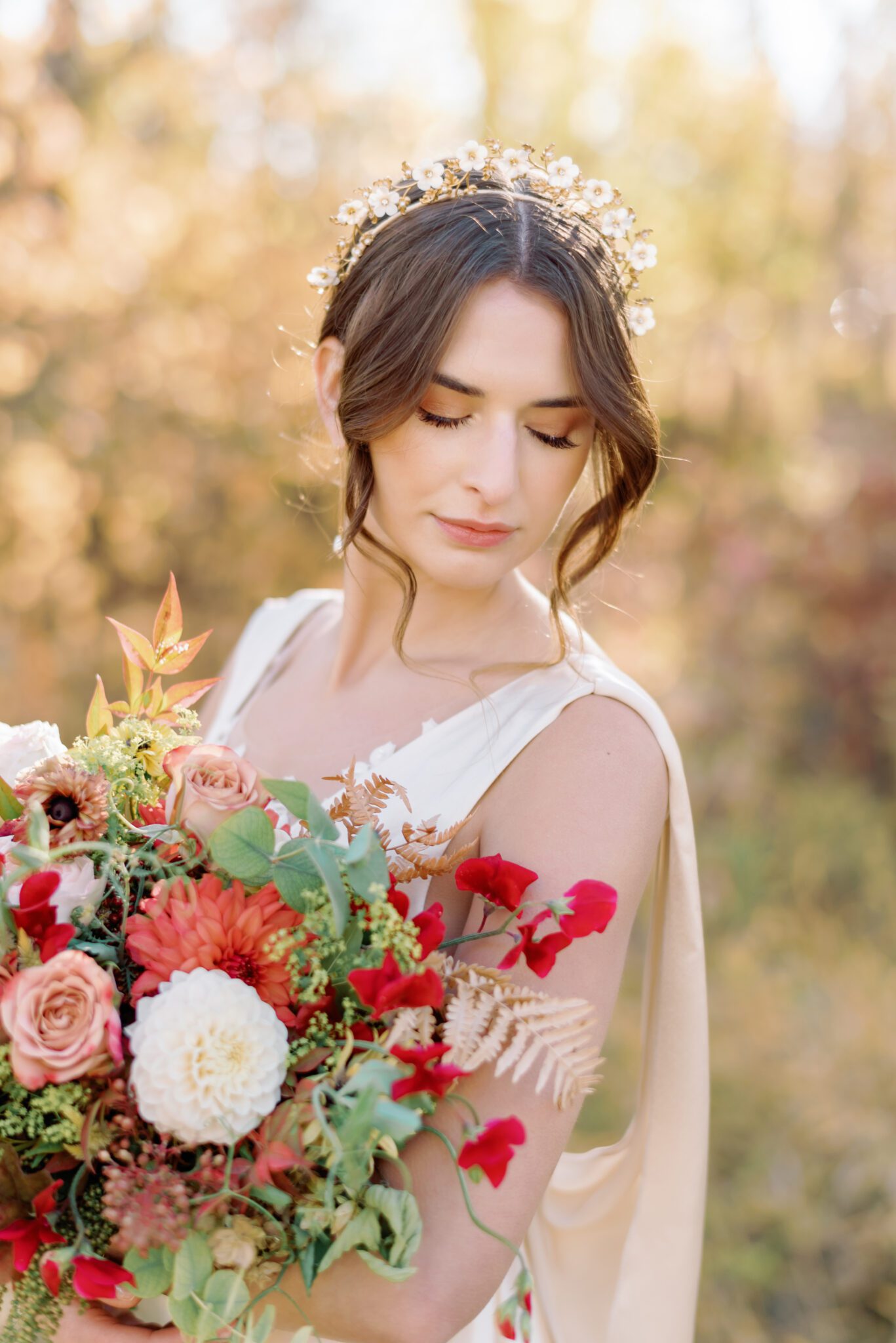 Bride wearing elegant champagne-toned satin wedding gown holding organic fall floral arrangements by Petal and Stem.
