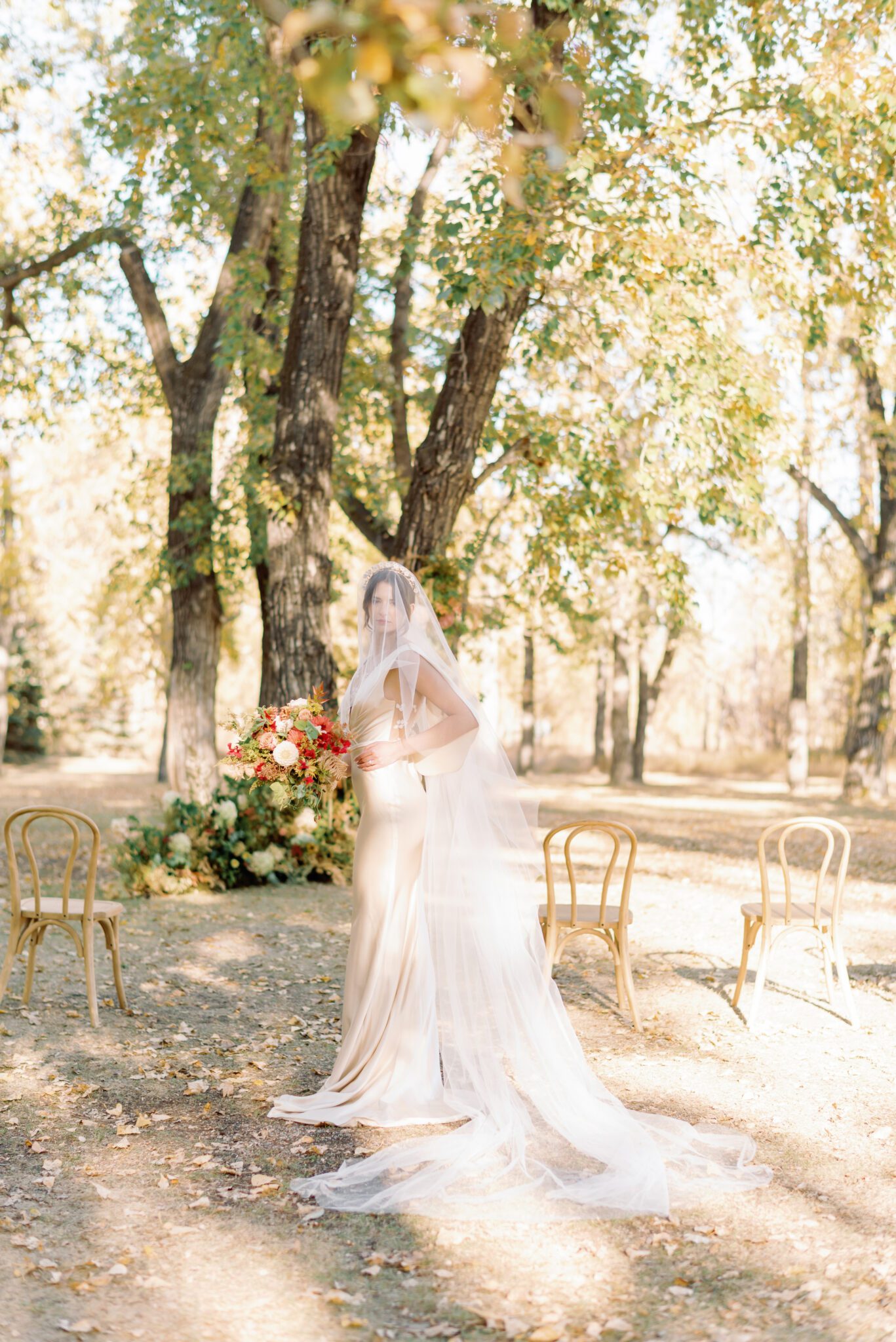 Bride wearing elegant champagne-toned satin wedding gown with cathedral length veil for this intimate autumn wedding inspiration.