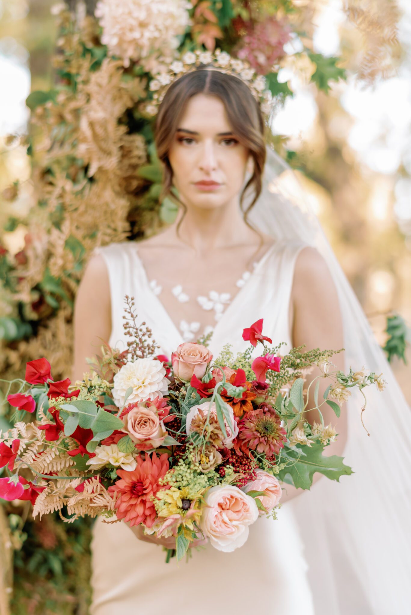 Bride wearing elegant champagne-toned satin wedding gown by Samantha Victoria, holding organic fall floral arrangements by Petal and Stem.
