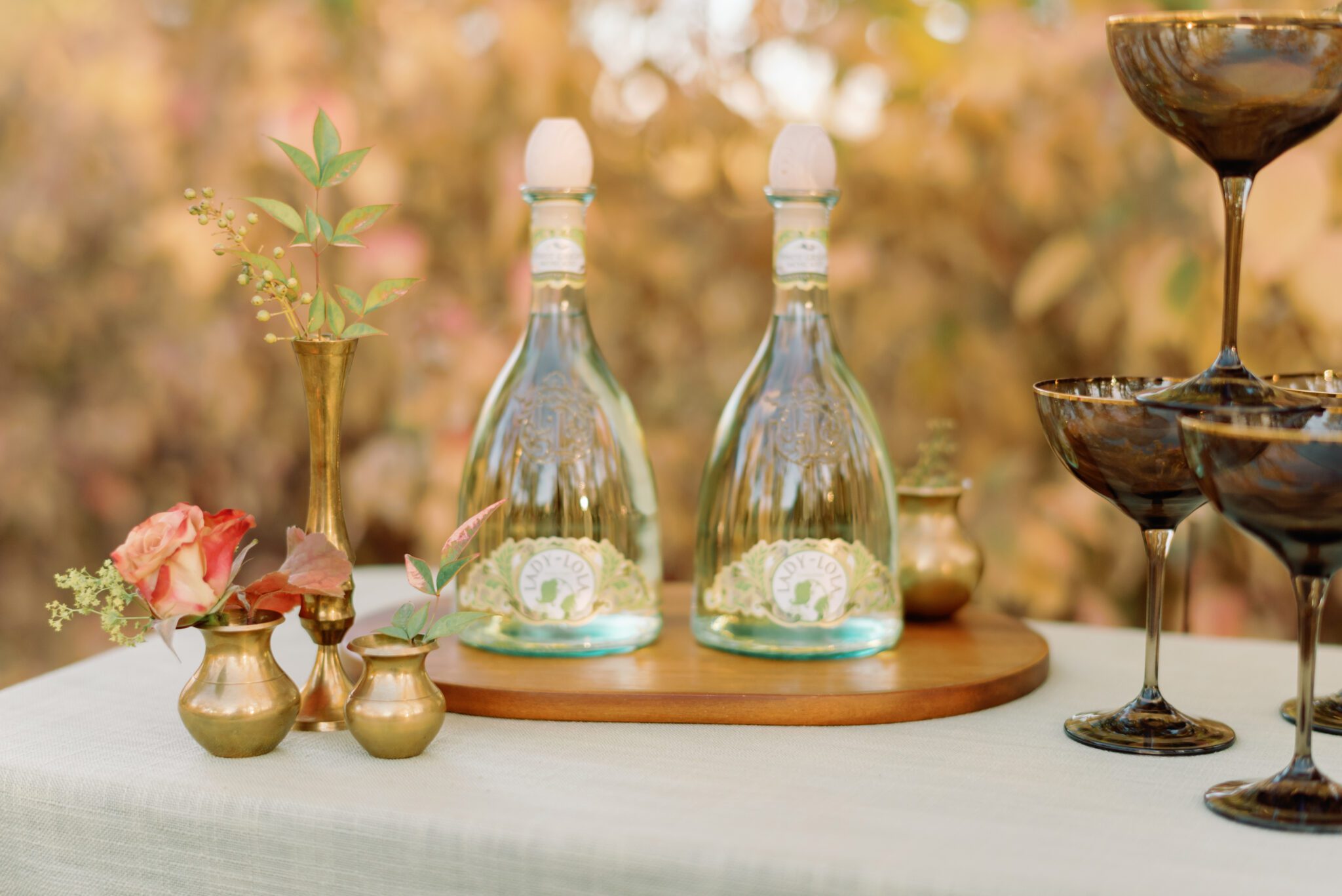 Outdoor champagne table featuring champagne bottles with uniquely elegant green-tinted glass. Al fresco dining at golden hour. Intimate autumn wedding designed and planned by Rebekah Bronte. 