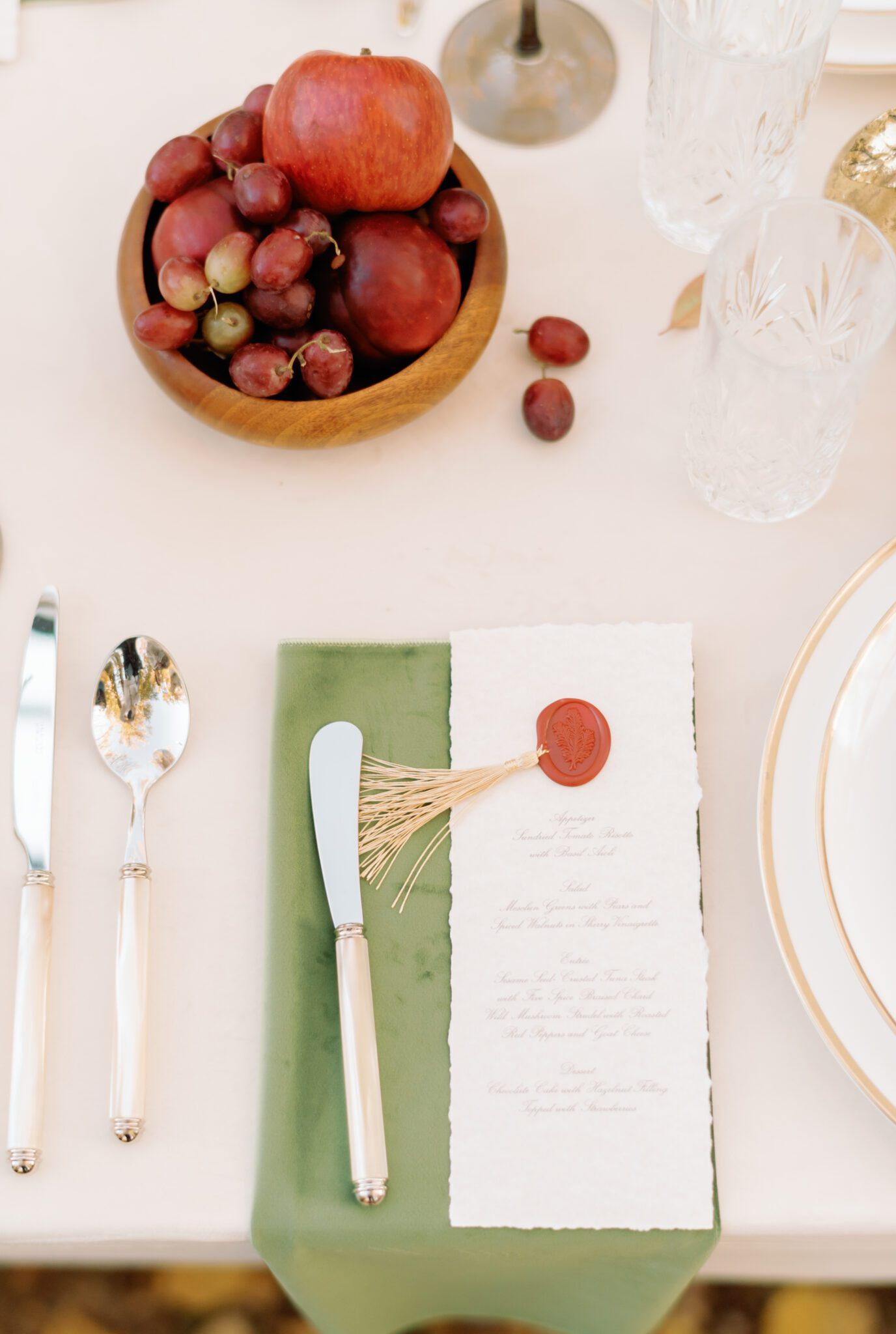 Al fresco dining at golden hour. Wedding reception tablescape featuring olive green, burgundy and rust details, elegant menus with crimson wax seals and gold tassel accents.