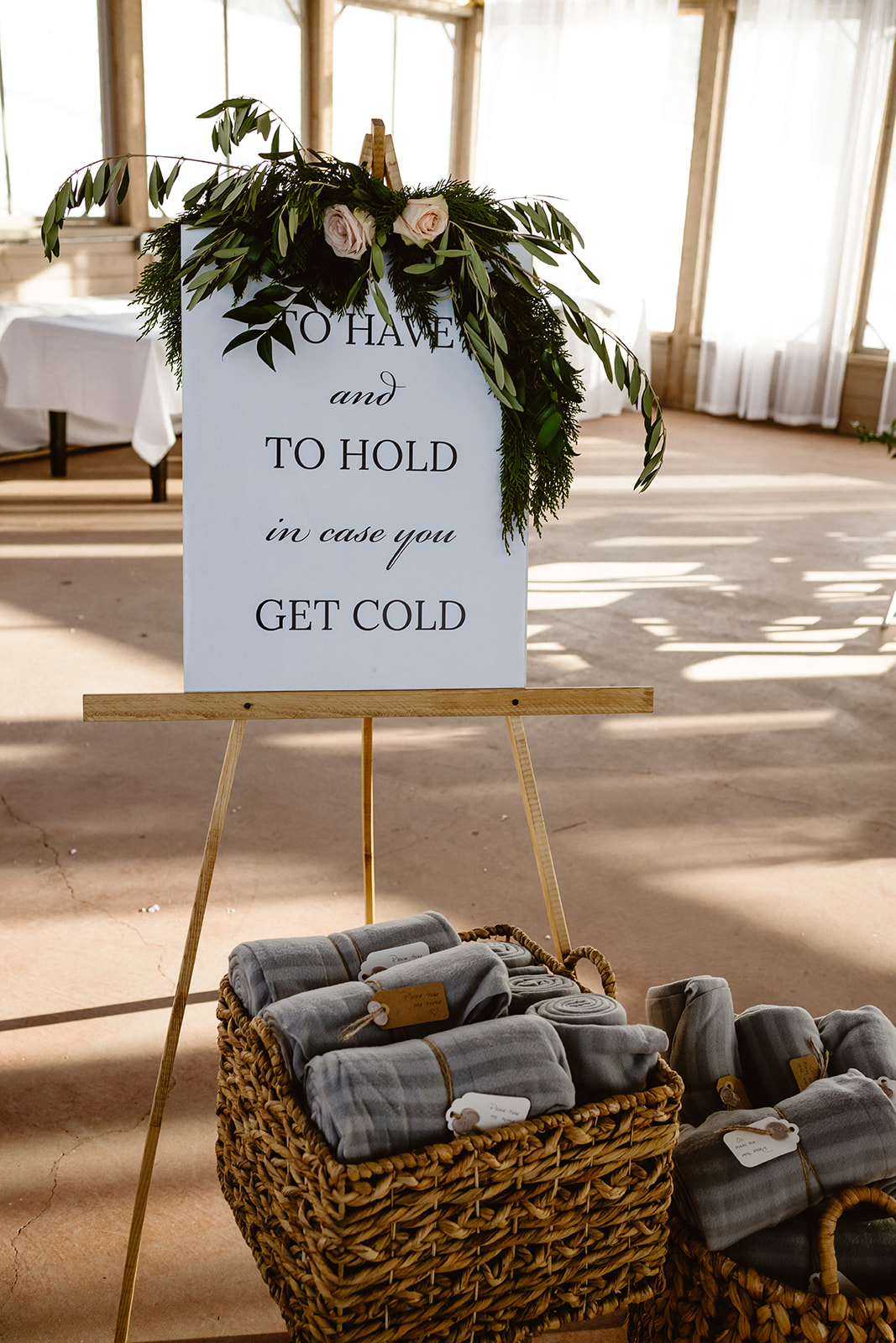 Welcome wedding signage with floral arrangement and warm blankets for guests to use, winter wedding inspiration. 