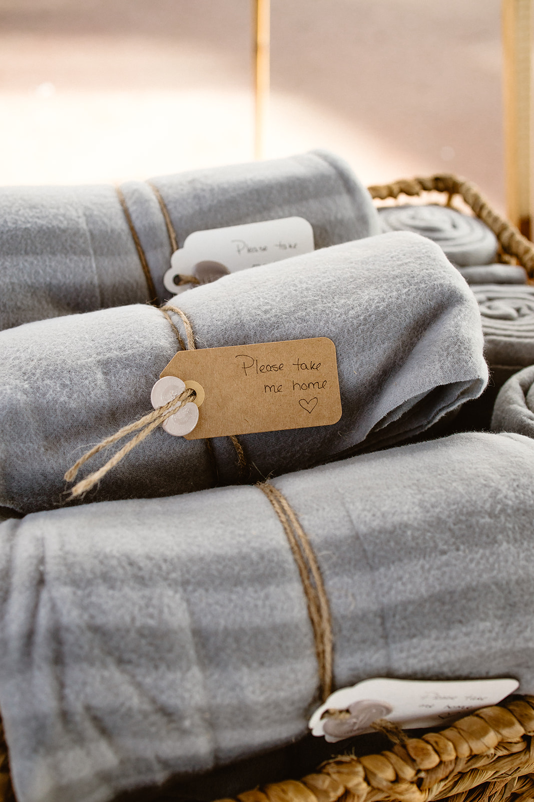 Grey blankets in a basket with custom tags as a favour for guests, winter wedding inspiration. 