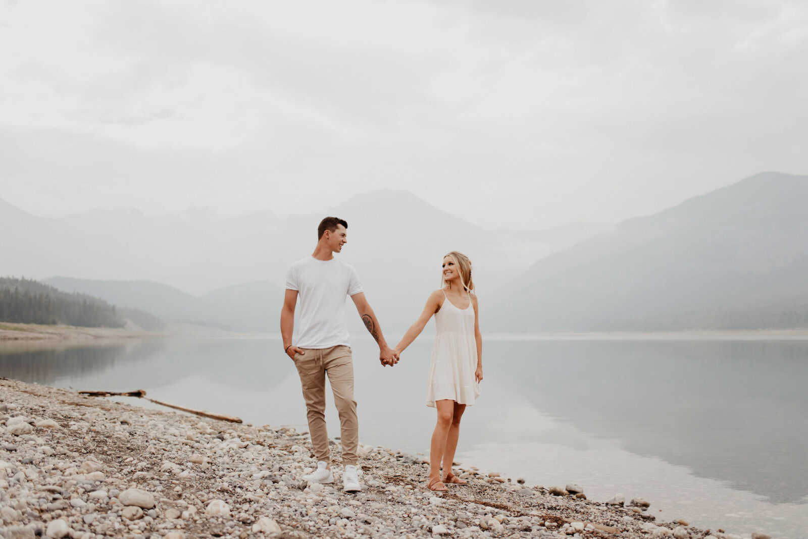 Engagement session inspiration, couple holding hand on the beach with Barrier Lake in the background. 