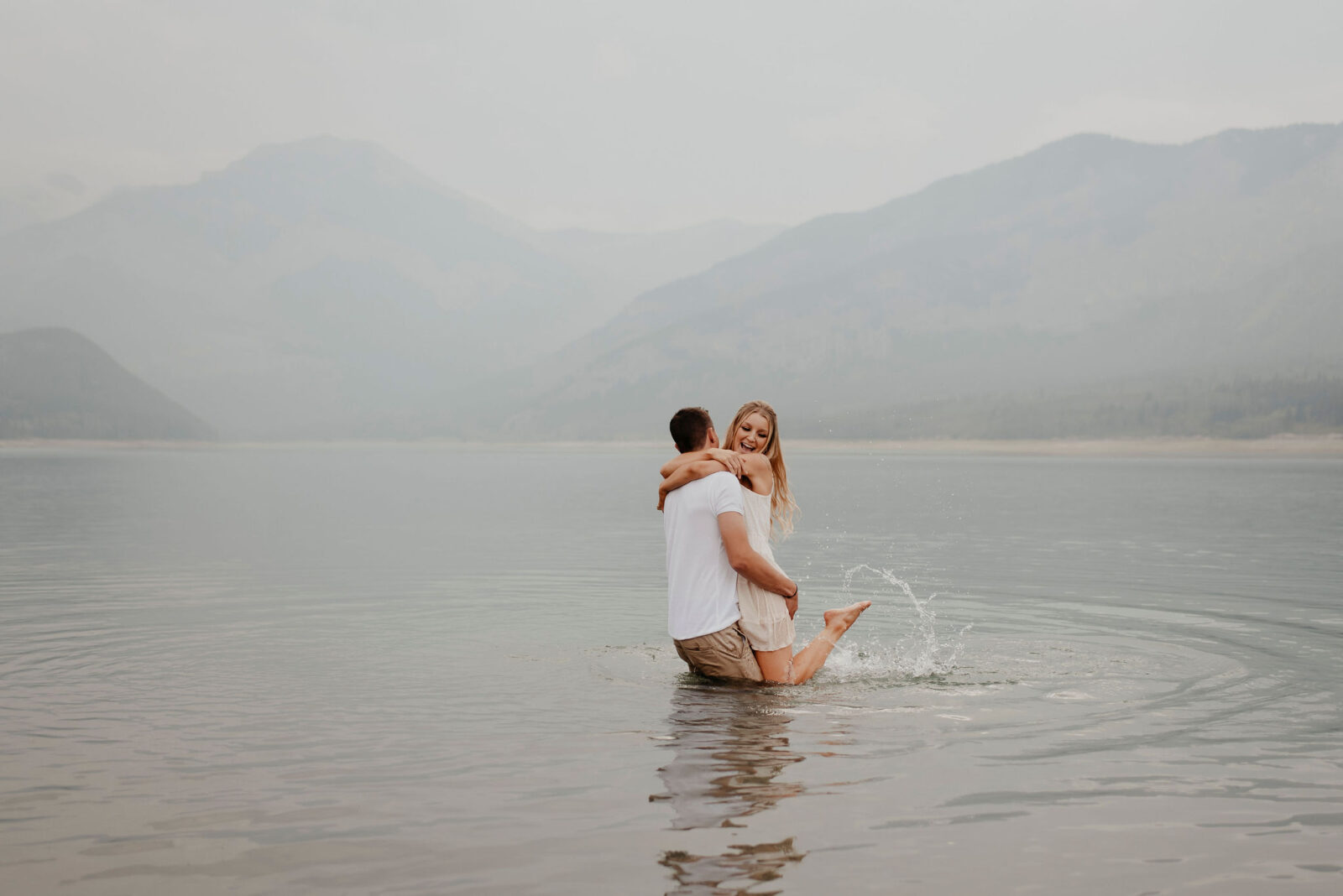 Fun couple playing in the water during their summer engagement session, captured by Alberta wedding photographer, Kelsey Vera.