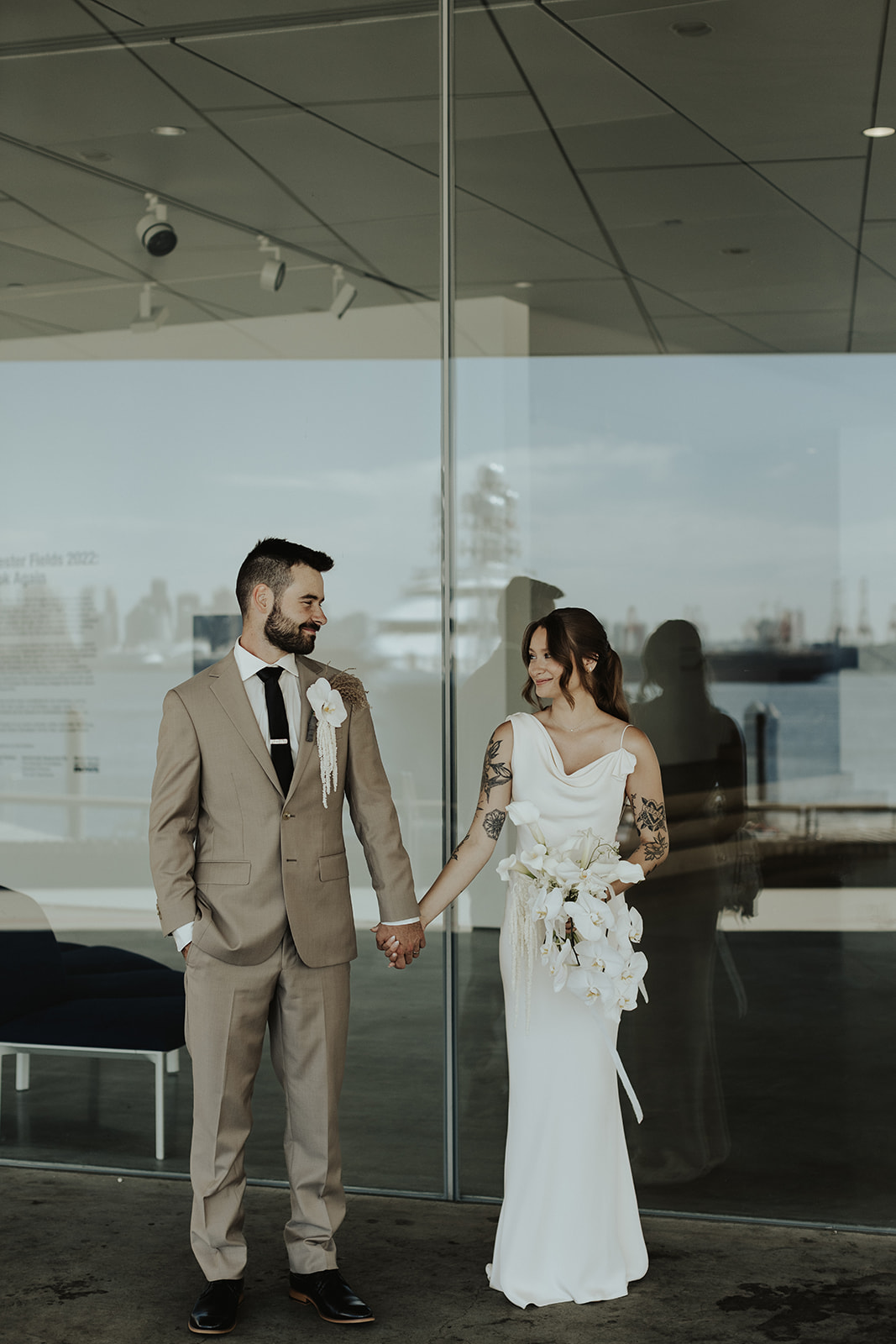 Modern tattooed bride and groom in North Vancouver, bride wearing sleek satin gown by Savannah Miller, holding stunning white orchid bouquet by The Flower Library.