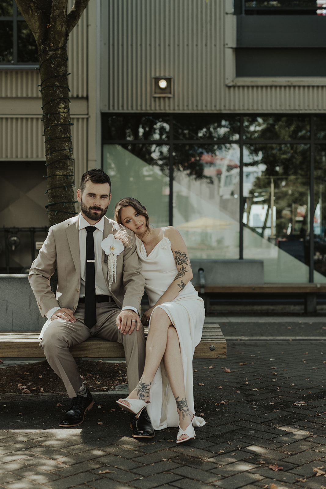Bride and groom sitting together on a bench downtown. Captured by Vancouver wedding photographers Jeff and Cat of The Apartment Photo.