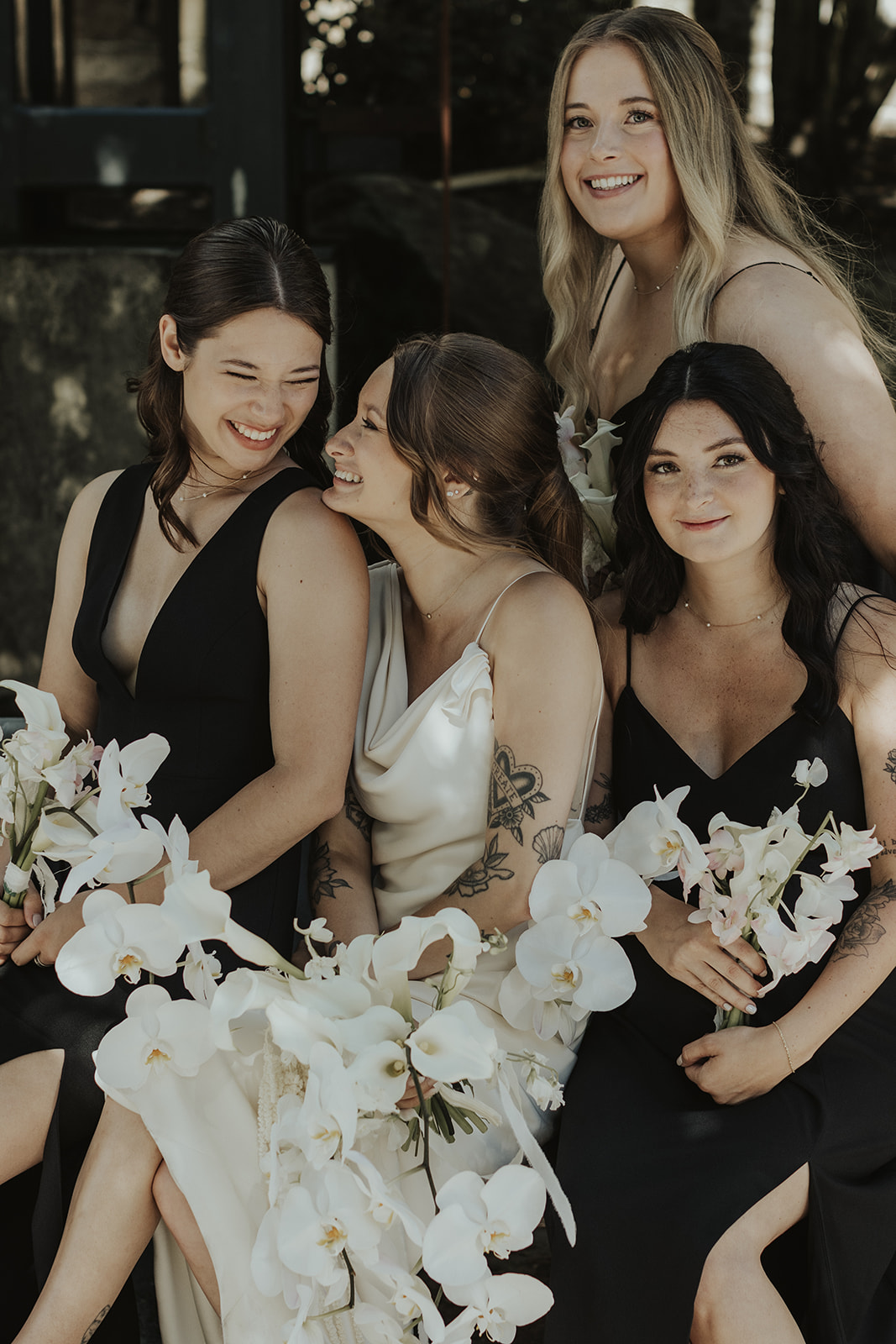 Bride with her bridesmaids in downtown Vancouver, black bridesmaids dresses and stunning white orchid bouquets by The Flower Library.