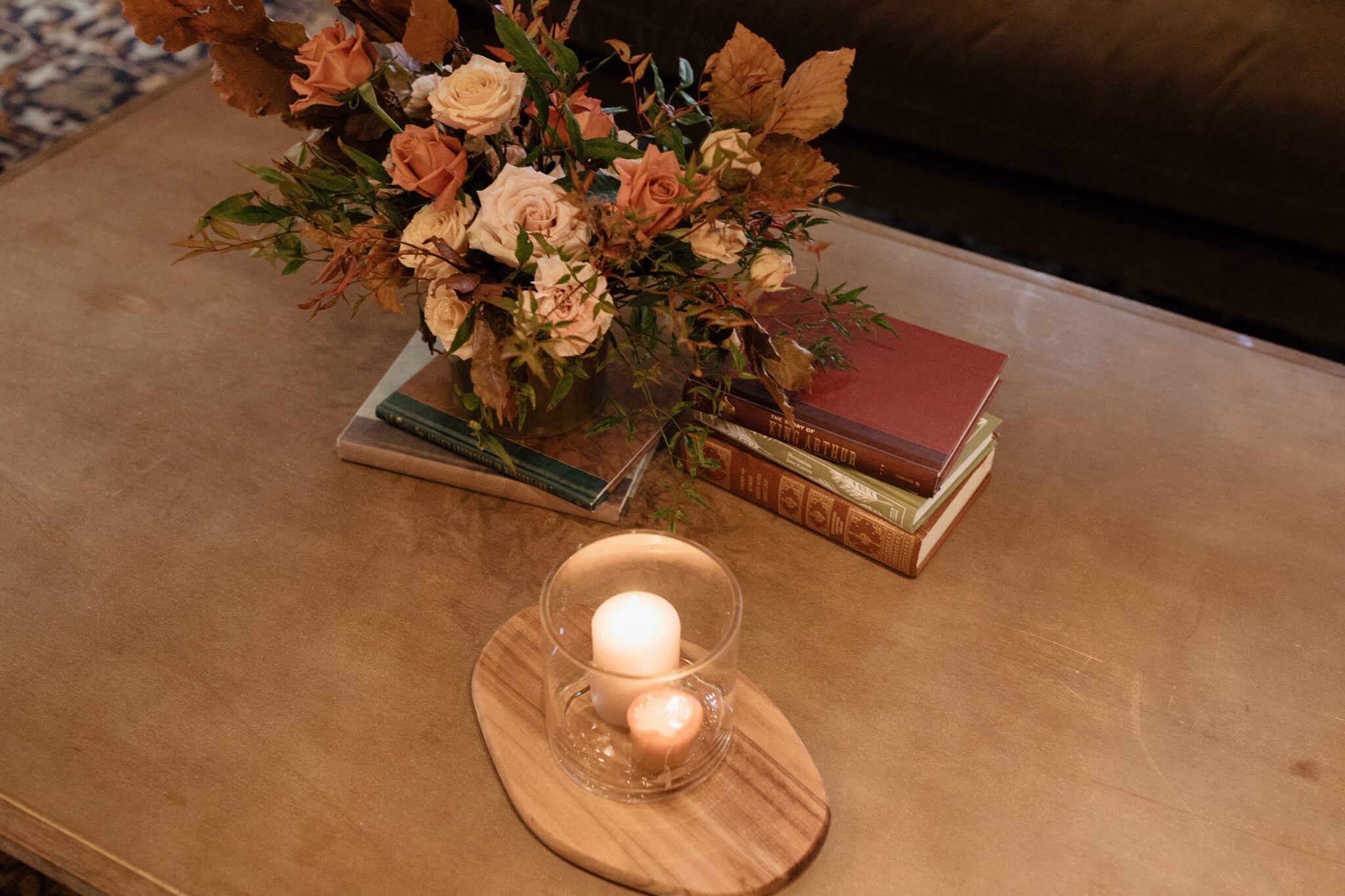 Warm, moody photography style at Silvertip Resort with a candle-lit lounge area filled with warm-toned florals, and vintage books, winter wedding inspiration. 