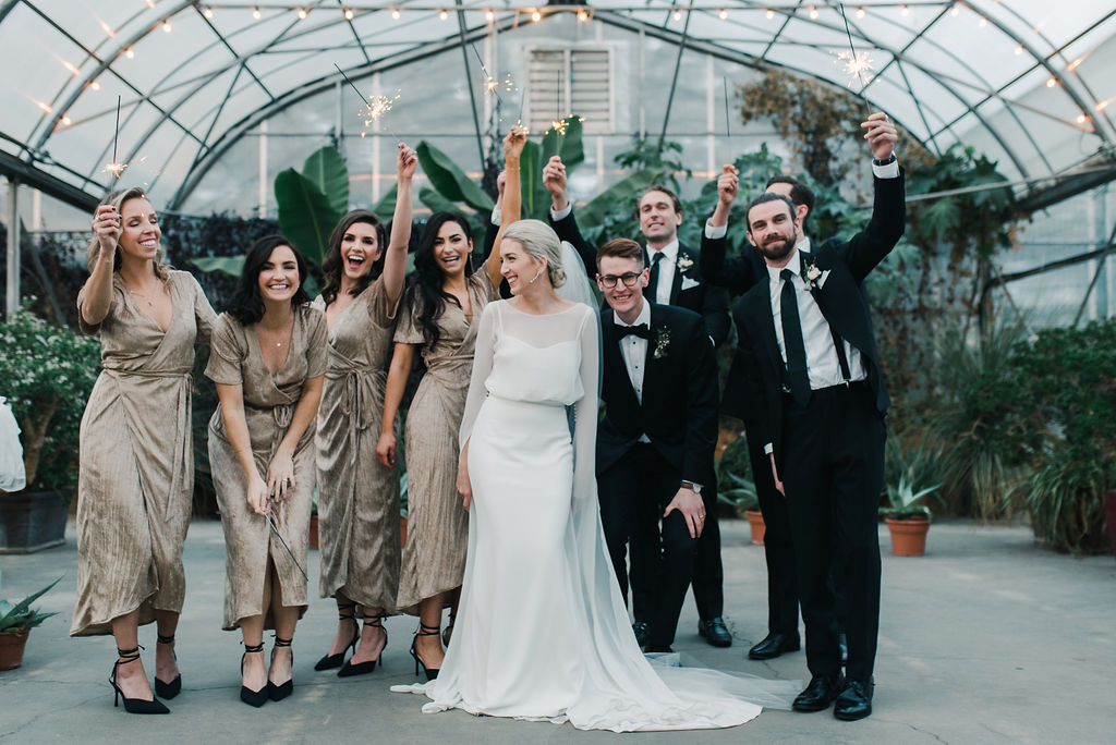 Portrait of bridesmaids and groomsmen holding sparklers, bridesmaids in gold gowns at Saskatoon Farm wedding venue, winter wedding inspiration. 