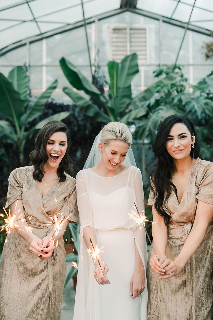 Bride and bridesmaids holding sparklers at New Year's Eve wedding, bridesmaids in gold gowns at Saskatoon Farm wedding venue, winter wedding inspiration. 