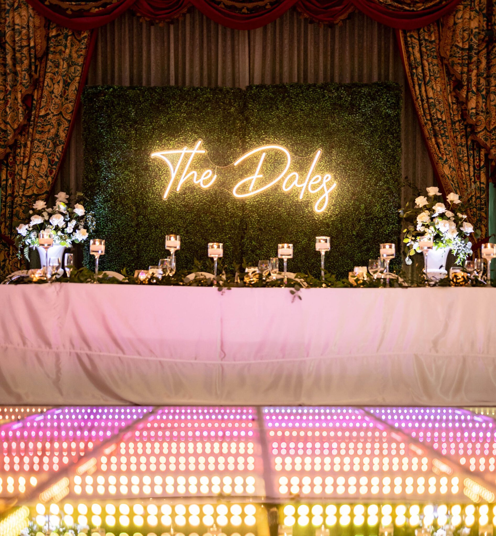 Eye-catching neon sign with couple's last name behind the head tablescape, wedding dance floor ideas. 