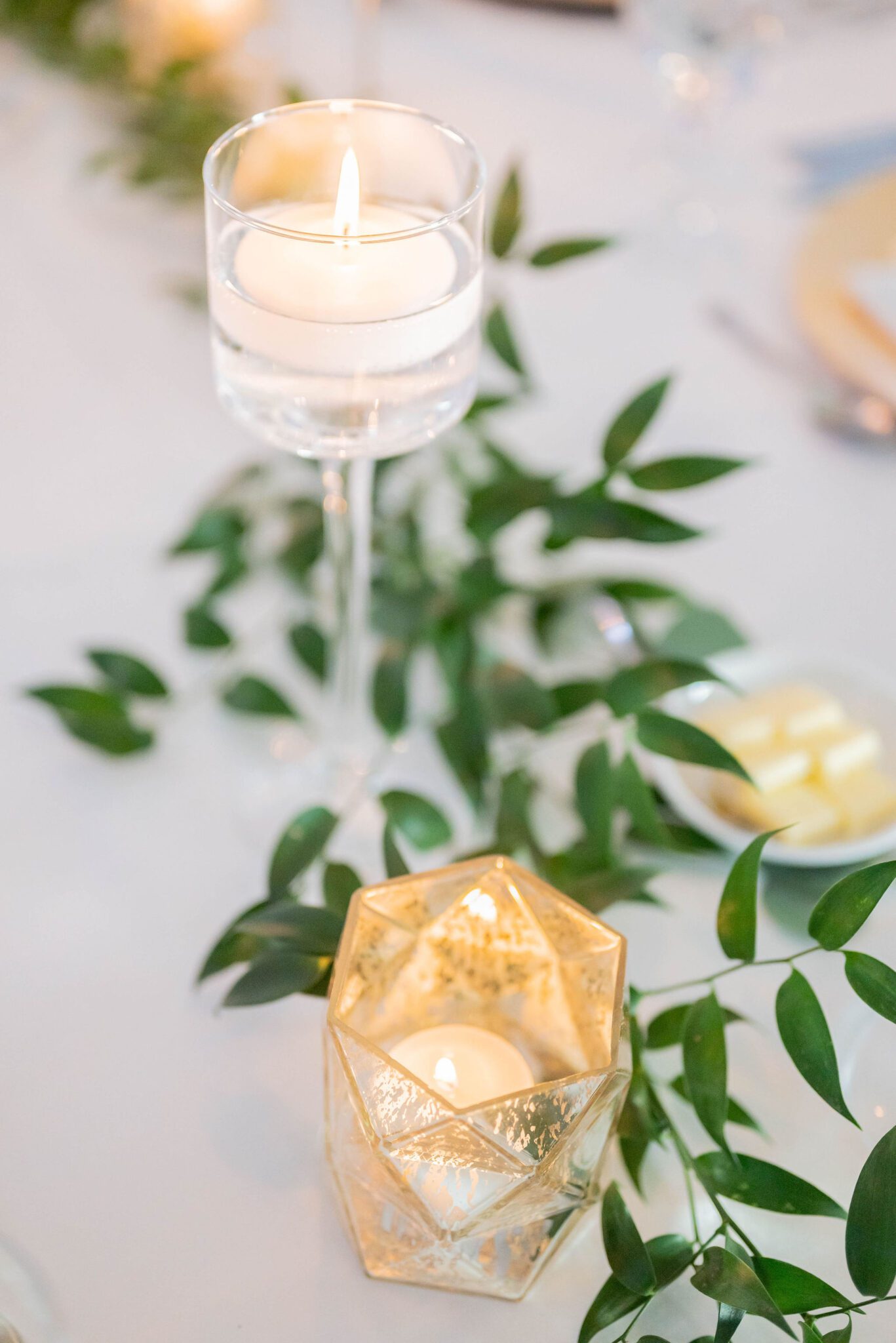 Classy votive candles added to the elegant tablescape, surrounded by greenery and gold candle holders. 