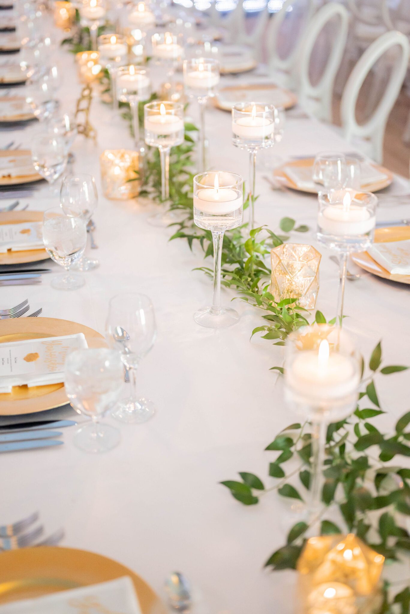 Candlelit reception tablescape with elegant greenery, gold-coloured charger plates with white linens at Banff Summer Wedding. 