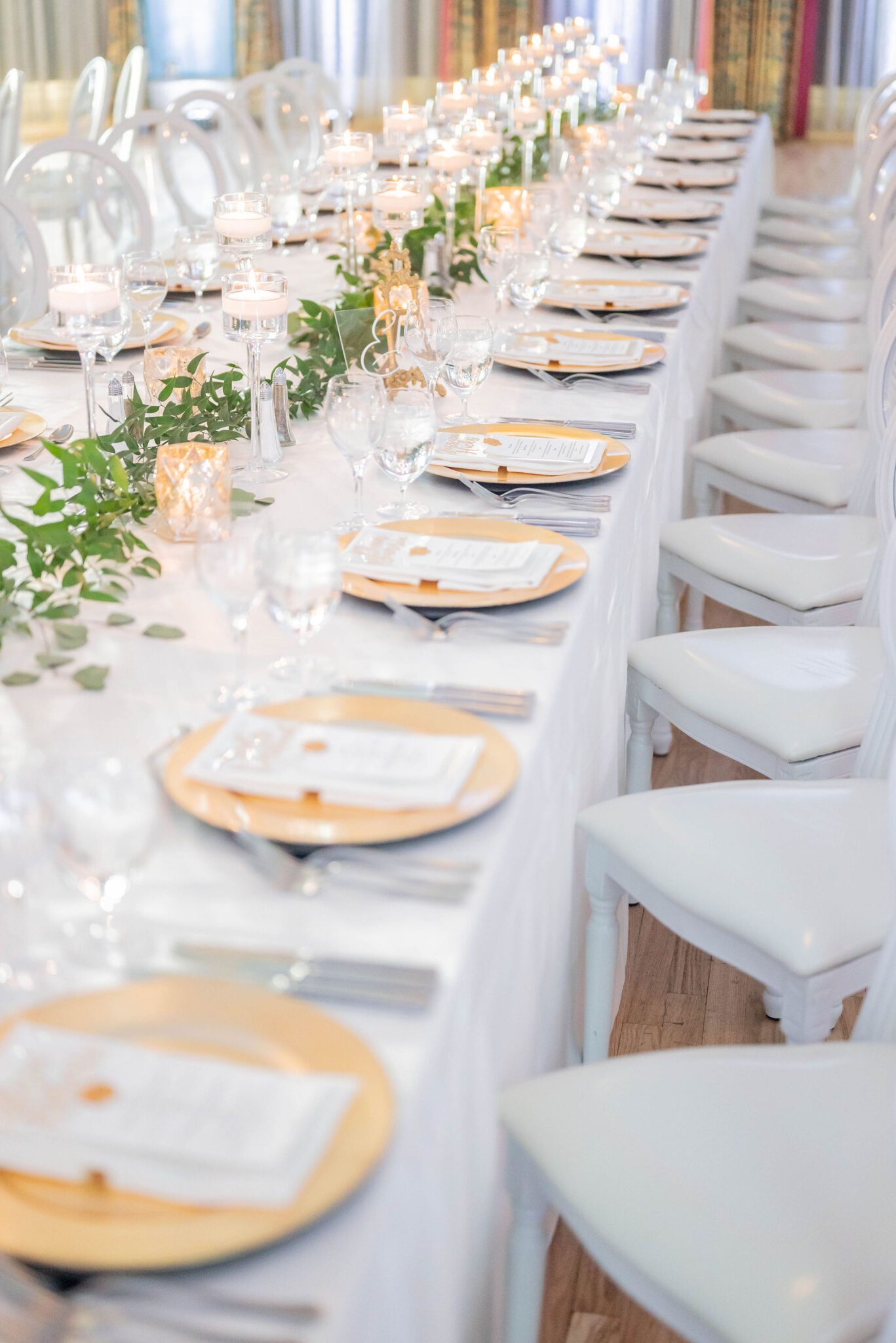 Banff wedding venue inspiration with elegant tablescape, white linens, greenery across the tablescape, gold detailing, and custom menus. 