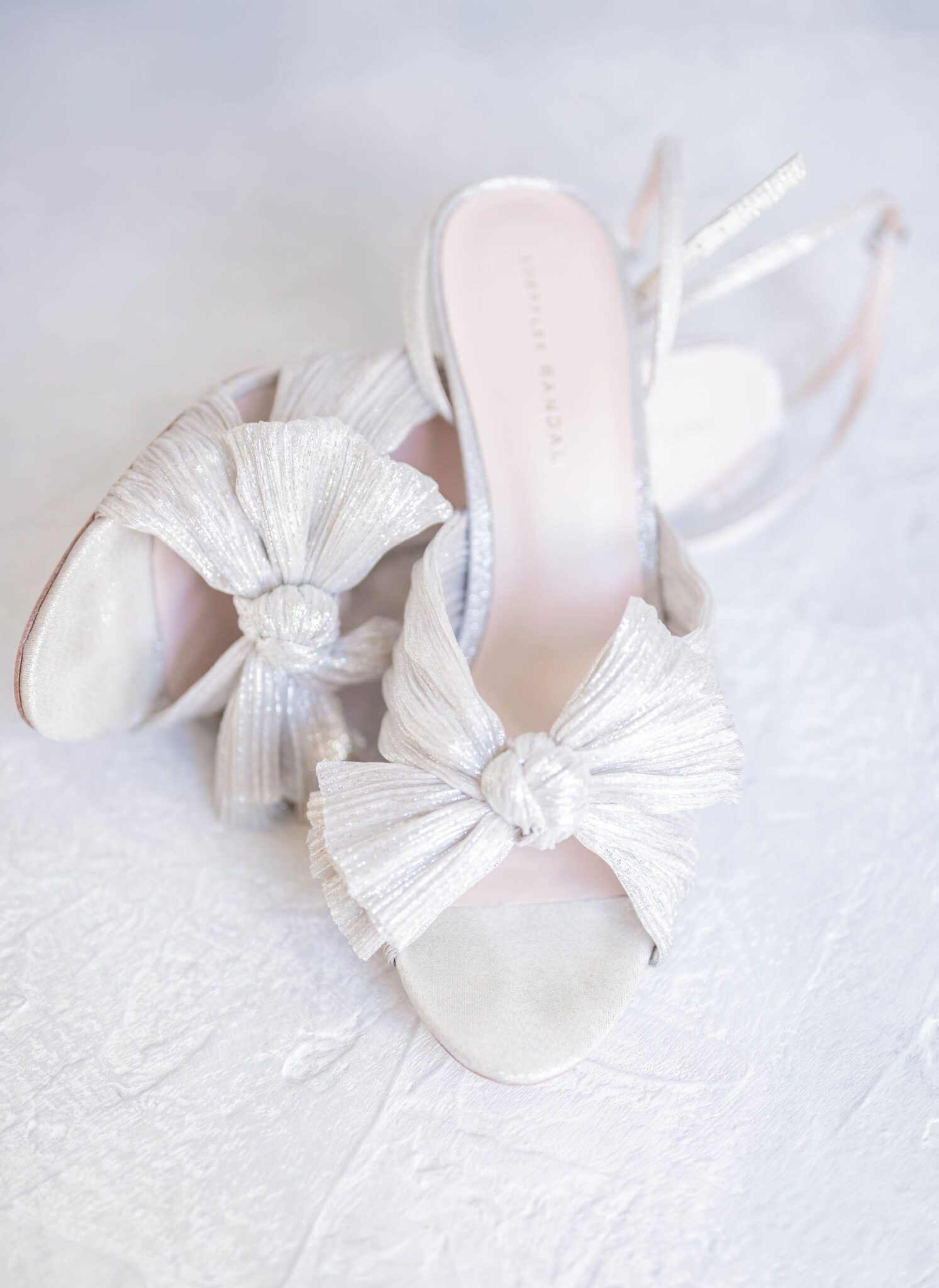 Elegant pearl-coloured bridal shoes with a fabric bow from Loeffler Randal.