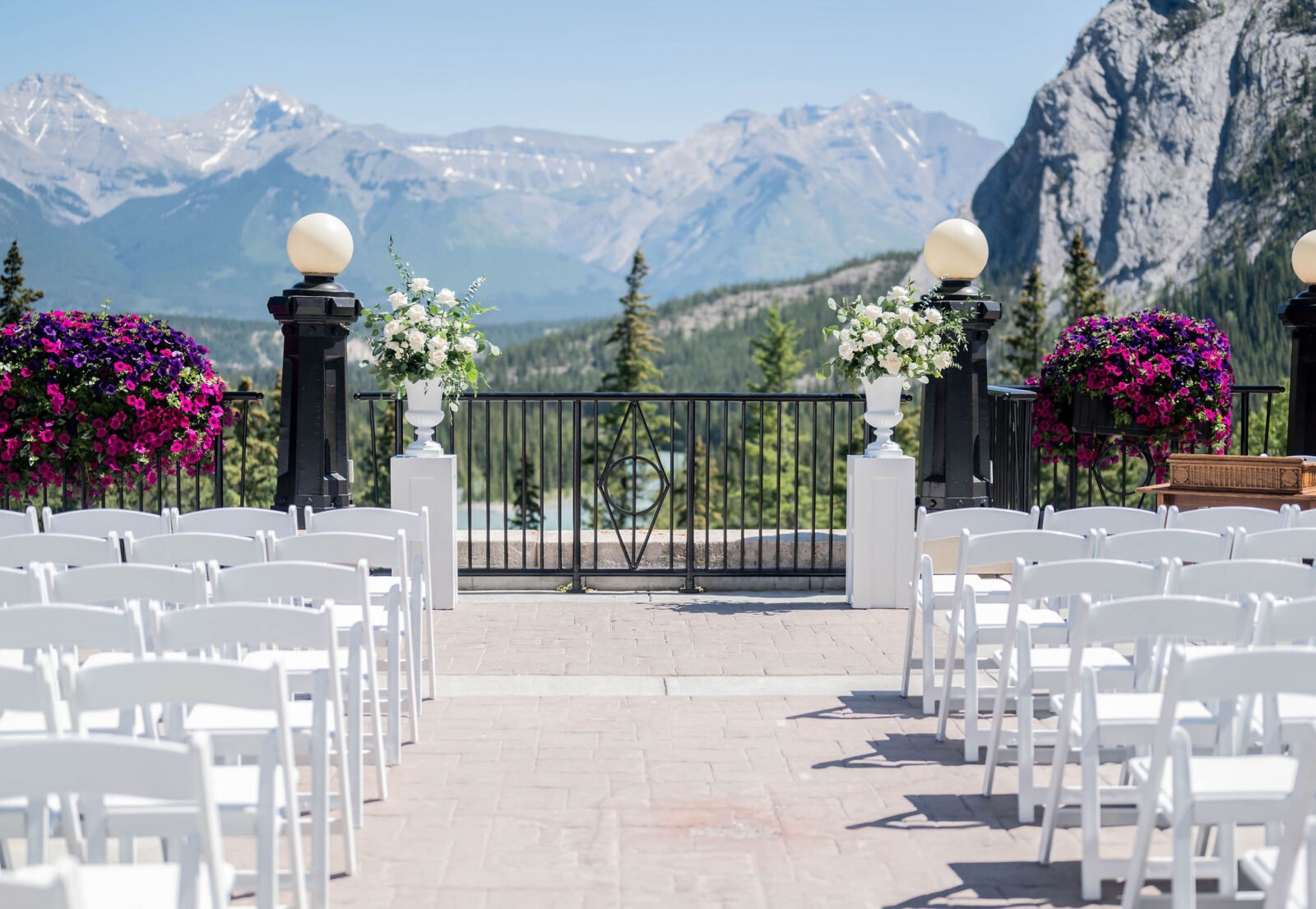 Banff summer wedding ceremony inspiration at the Fairmont Banff Springs, white florals with greenery on pedestals overlooking mountain view.