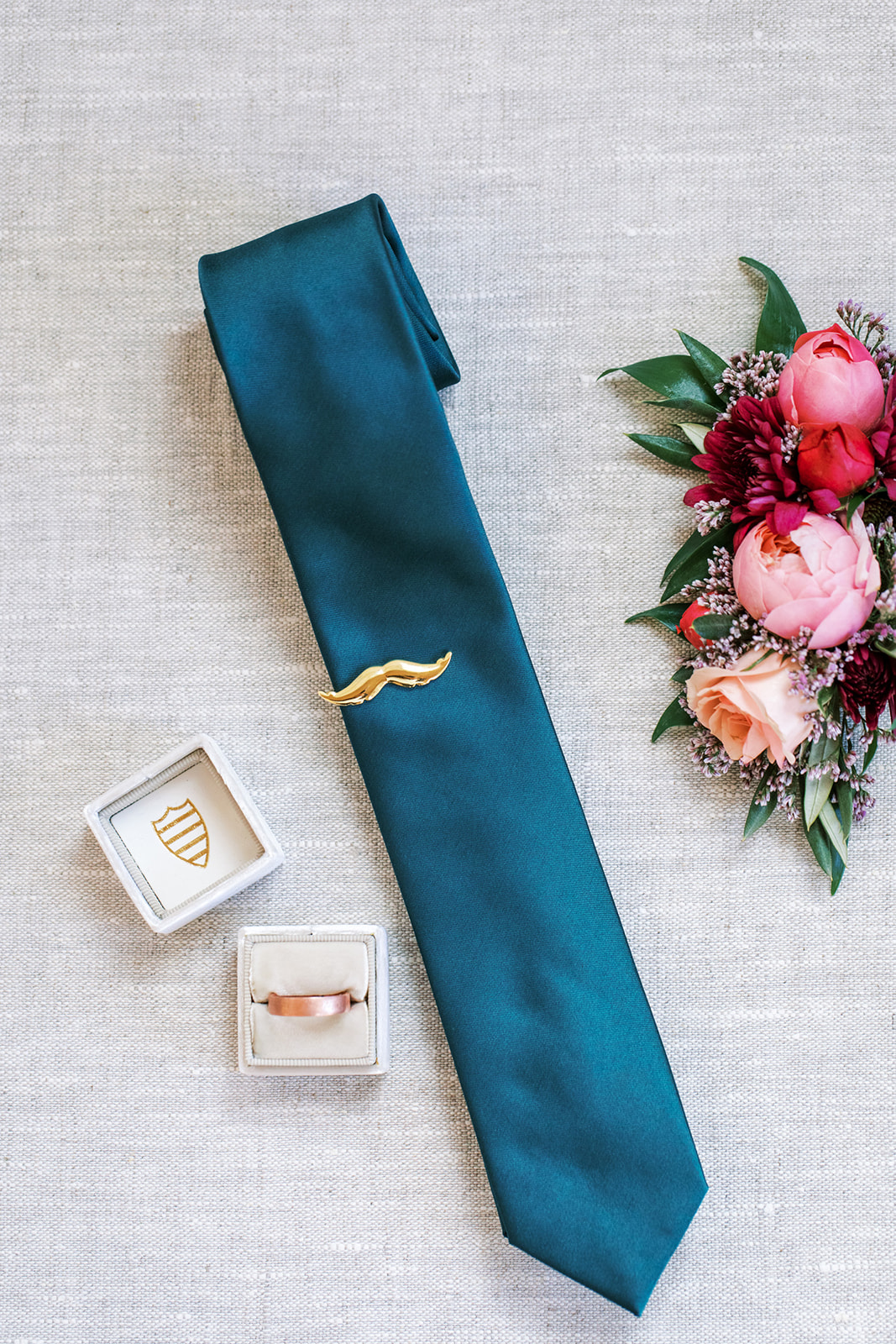 Colourful, vintage inspired pink boutonniere by Rose & Vine, and blue tie with mustache tie clip by Trinos Menswear.