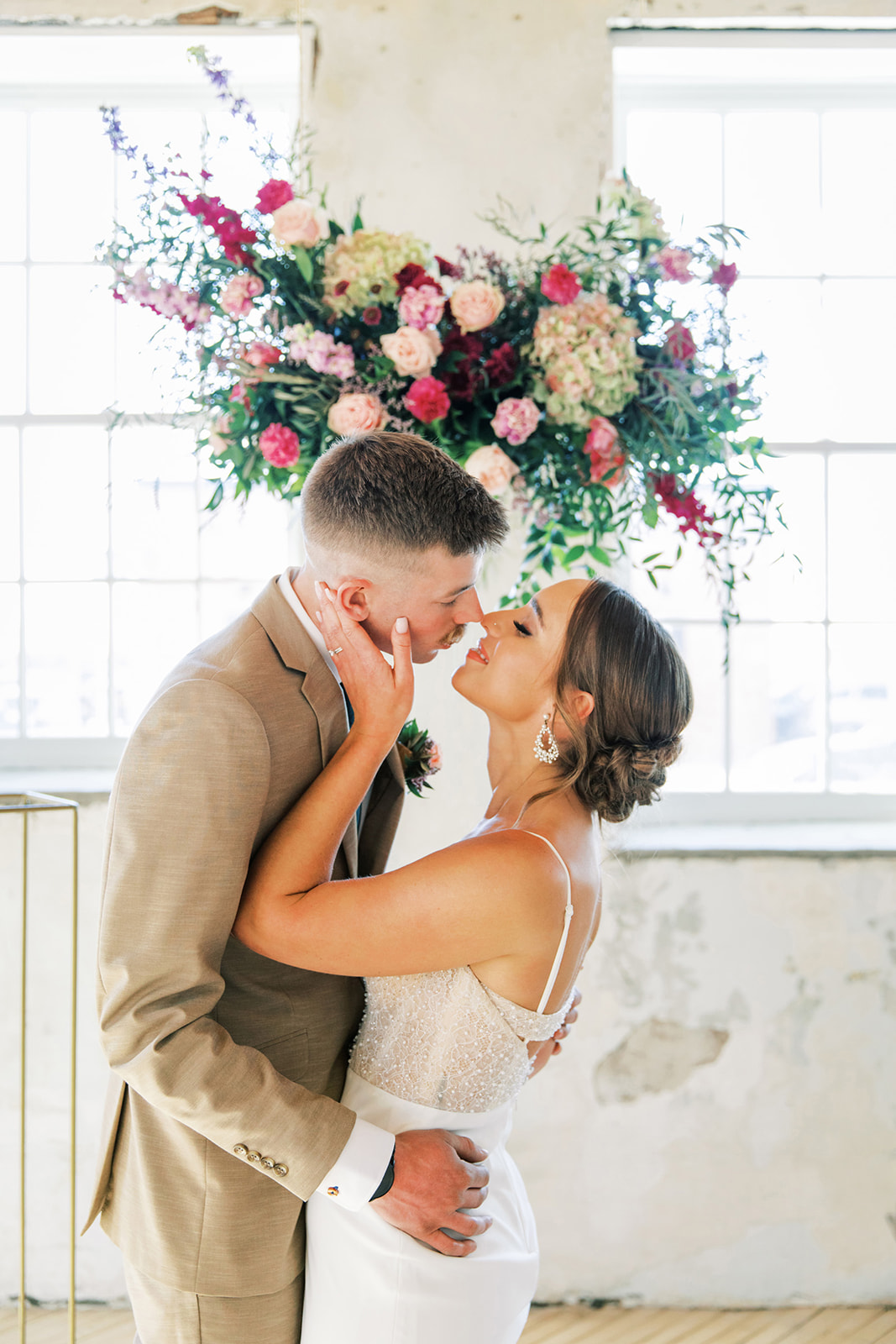 Couple kissing during romantic, vintage inspired wedding ceremony, featuring hanging florals created by Rose & Vine.