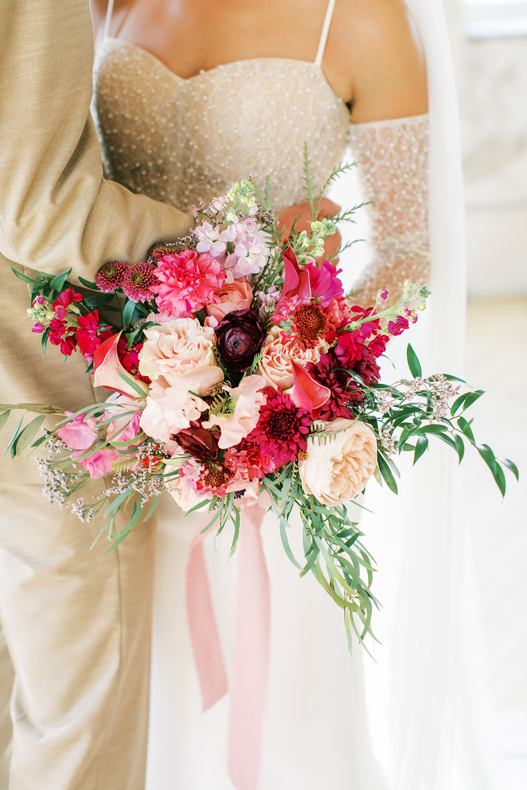 Brightly coloured bridal bouquet featuring a colour palette of pink, berry, blush, green, red, burgundy, and nude. 
