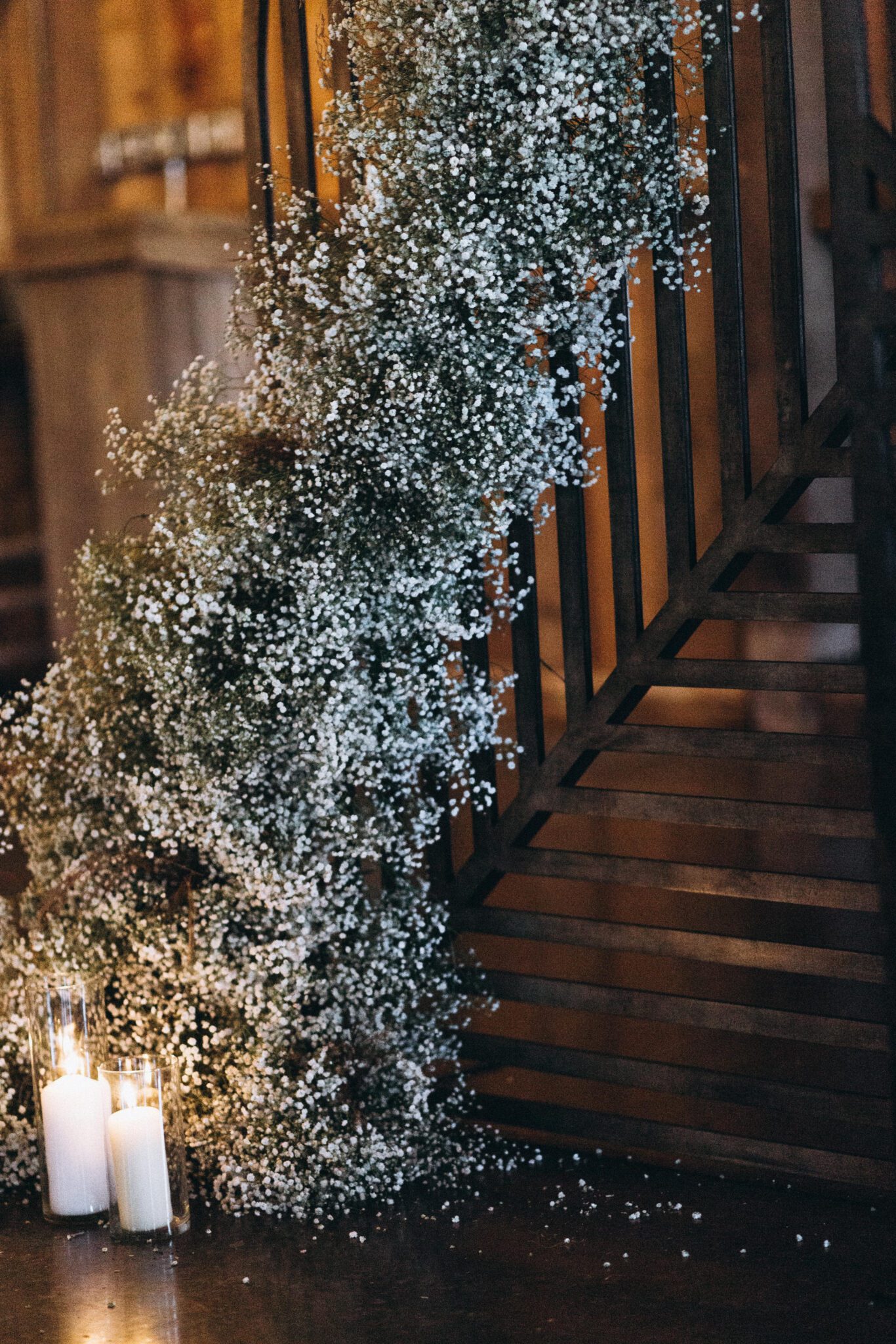 Modern whimsical baby's breath installation for the ceremony arch at this Country Chic wedding, paired with romantic candlelight for a warm cozy winter wedding ceremony.