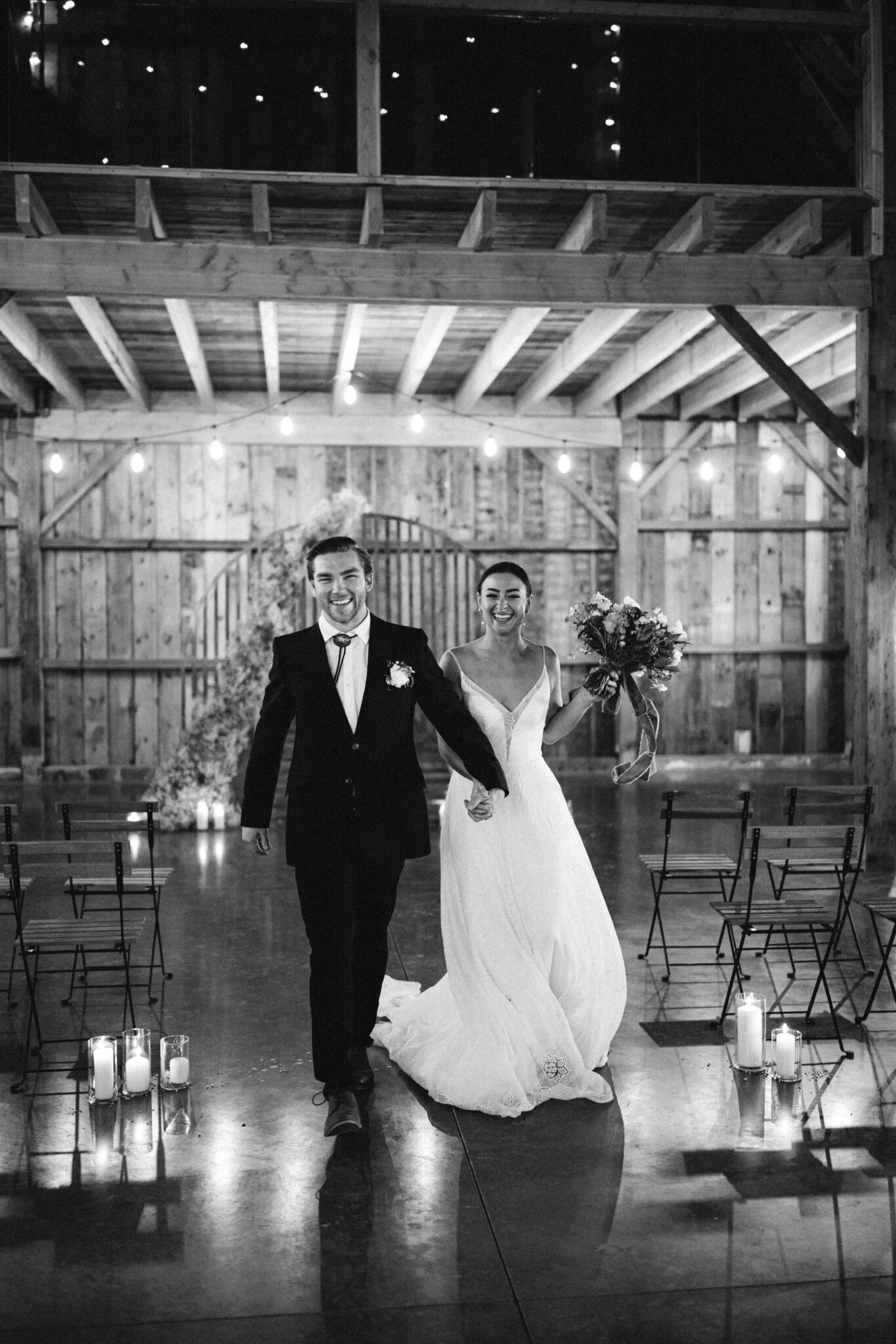 Modernized and updated take on a baby's breath installation for the ceremony arch at this Country Chic style wedding inspiration at Countryside Barn in Lethbridge Alberta, bride and groom walking down the aisle after saying "I Do", black and white photography, modern country wedding style. 