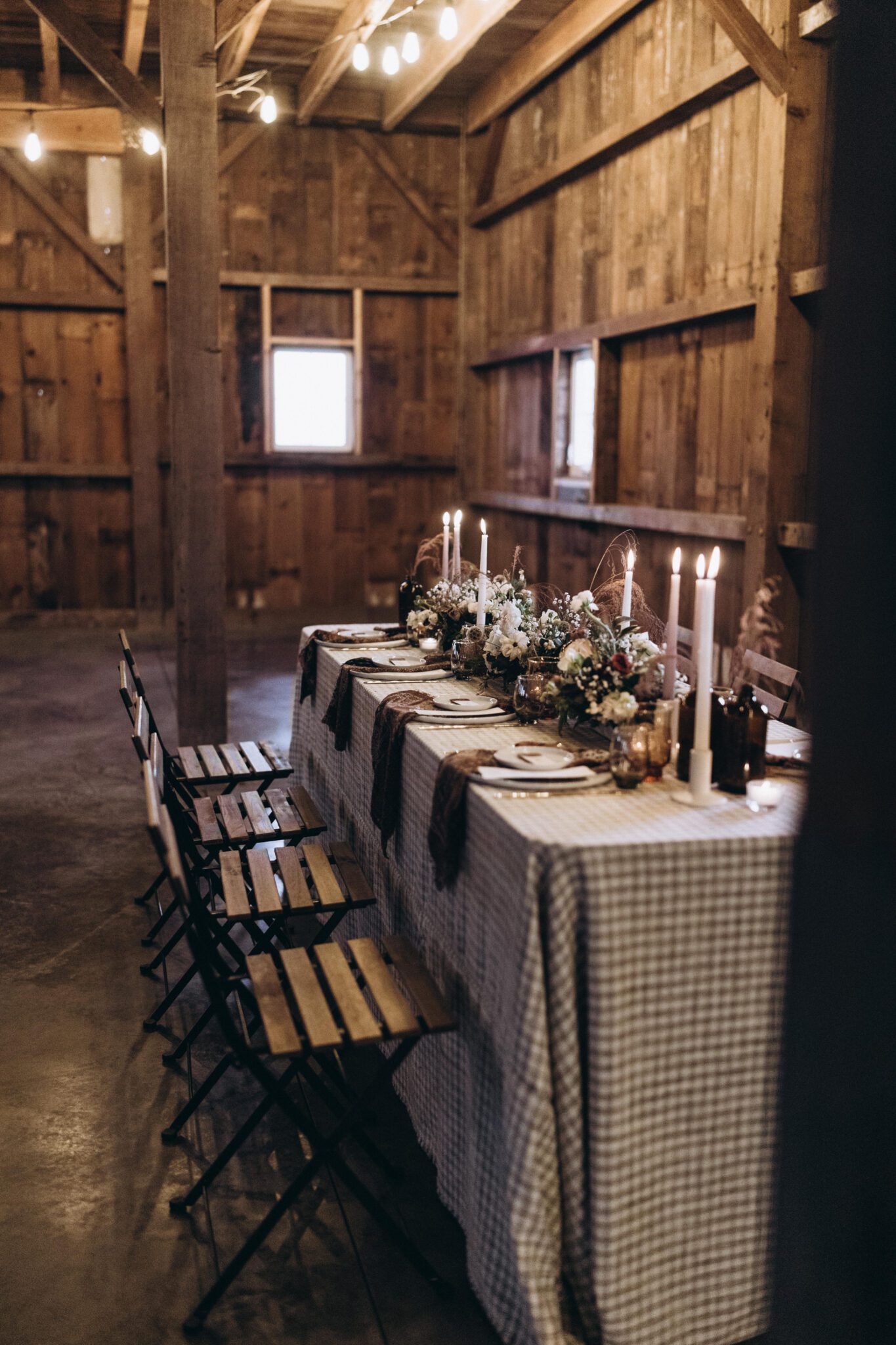 Country Chic style wedding inspiration with patterned tablescape, checkered and textured linens, unique and earthy florals covering the table, candle-lit style dinner. 