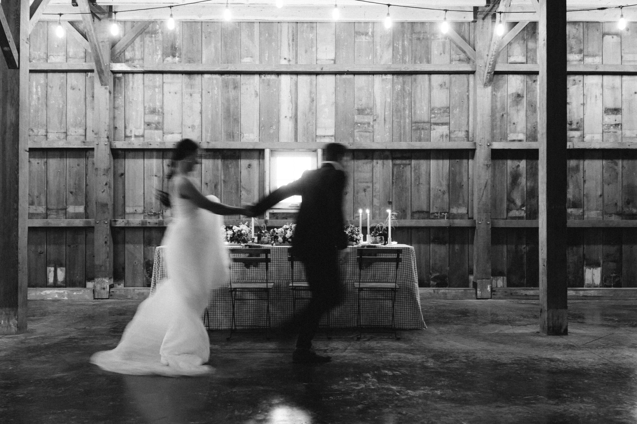 Wedding Inspiration With An Updated Take on Country Chic Wedding Style at Countryside Barn in Lethbridge Alberta, modern wedding photography style, couple running in front of wedding table, blurred photography style