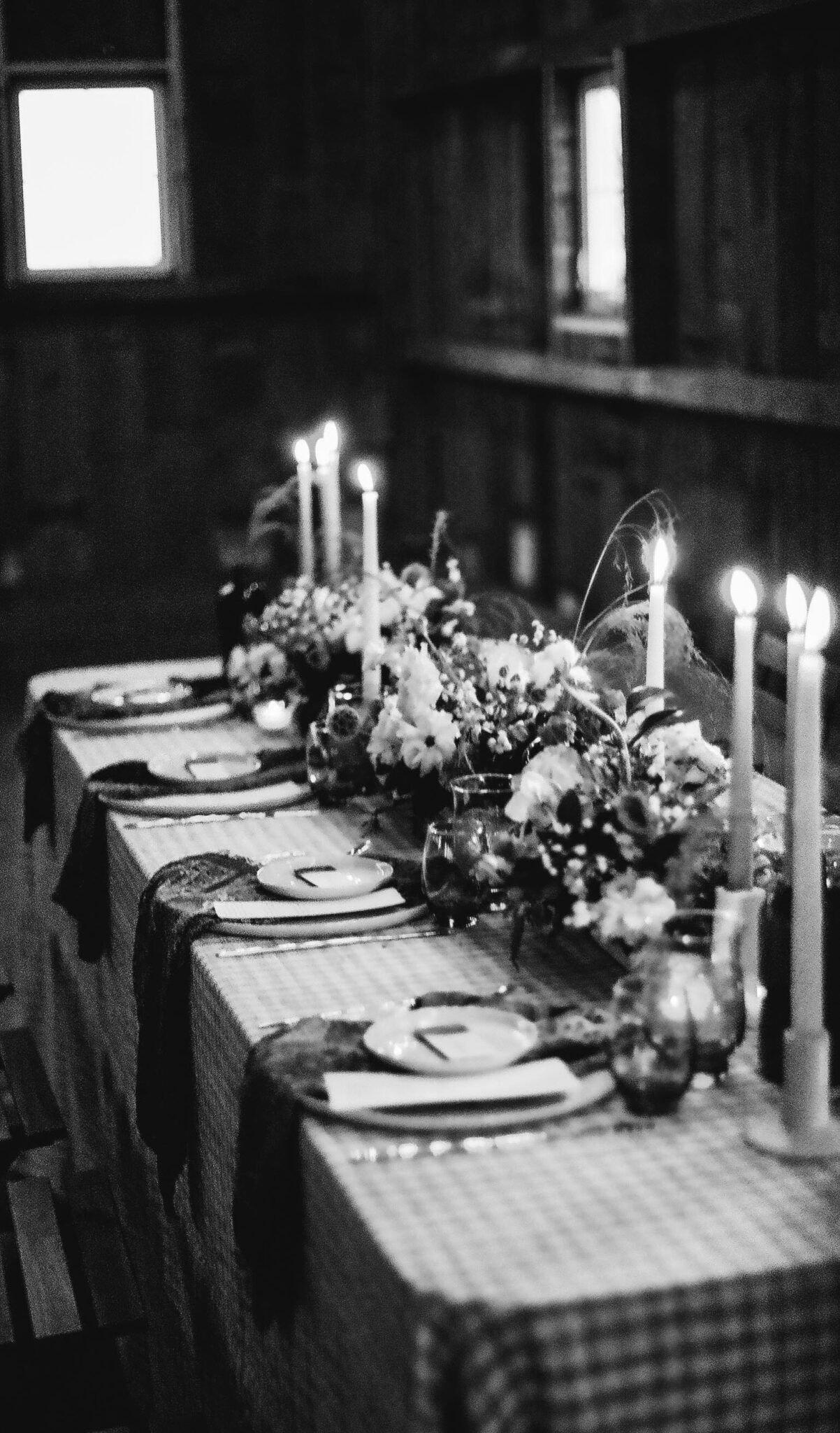 Black and white photo of country chic tablescape design at Countryside Barn, in Lethbridge, Alberta, candle lit atmosphere, with patterned linens.