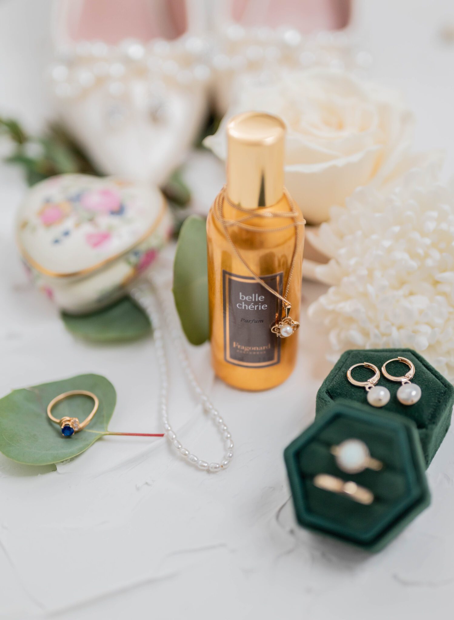 Close up detail photo of Belle Chérie perfume and gold bridal jewelry, with pearl detailing. 