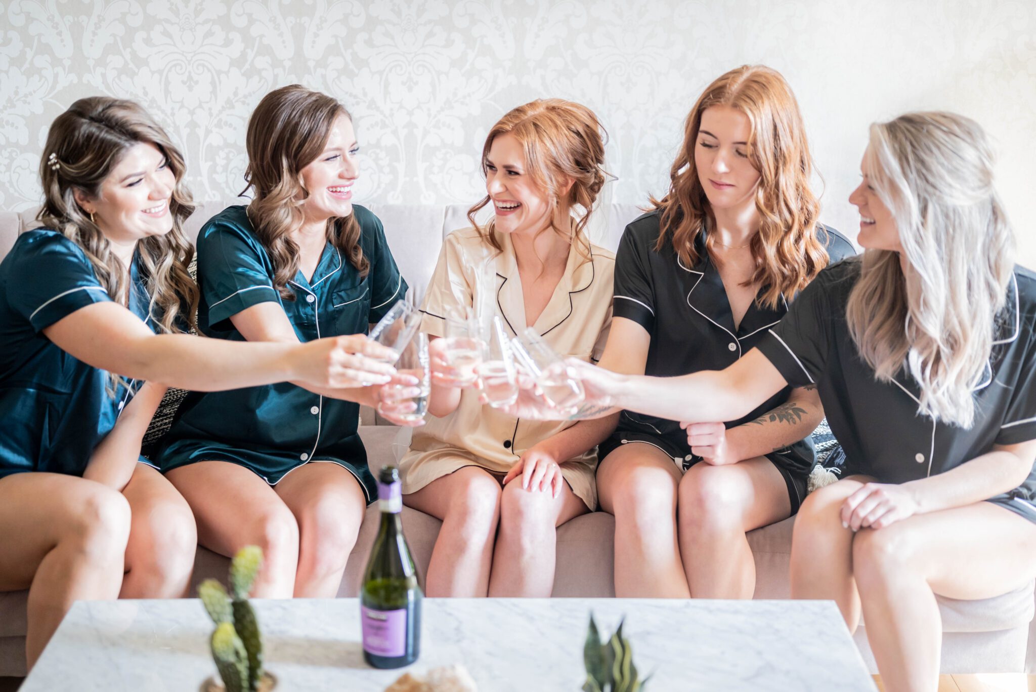 Bride and bridesmaids celebrating with glasses of champagne in the charming getting ready suite. 