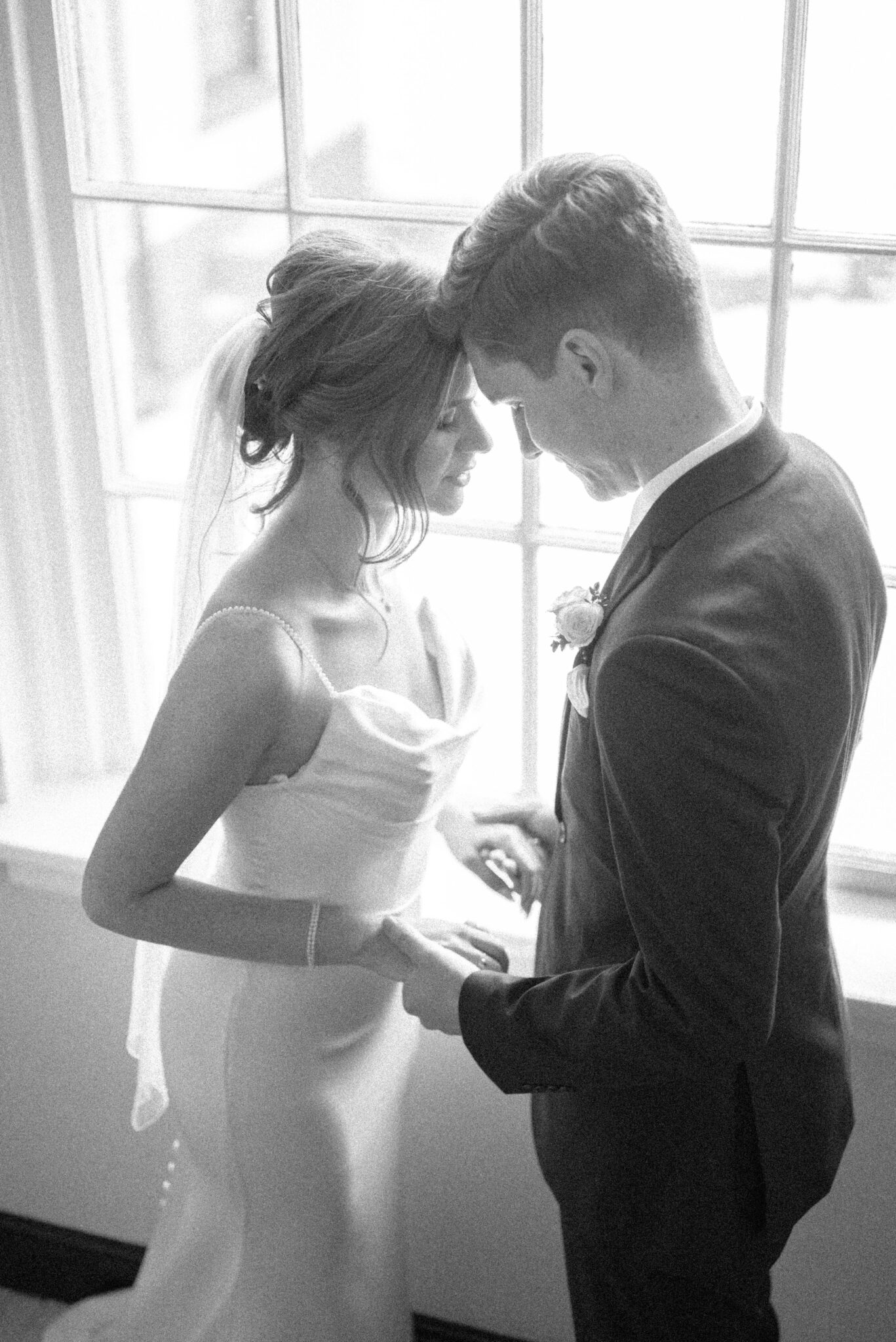 Black and white portrait of bride and groom in front of windows facing each other, bridal portrait inspiration, classic Calgary wedding inspiration. 