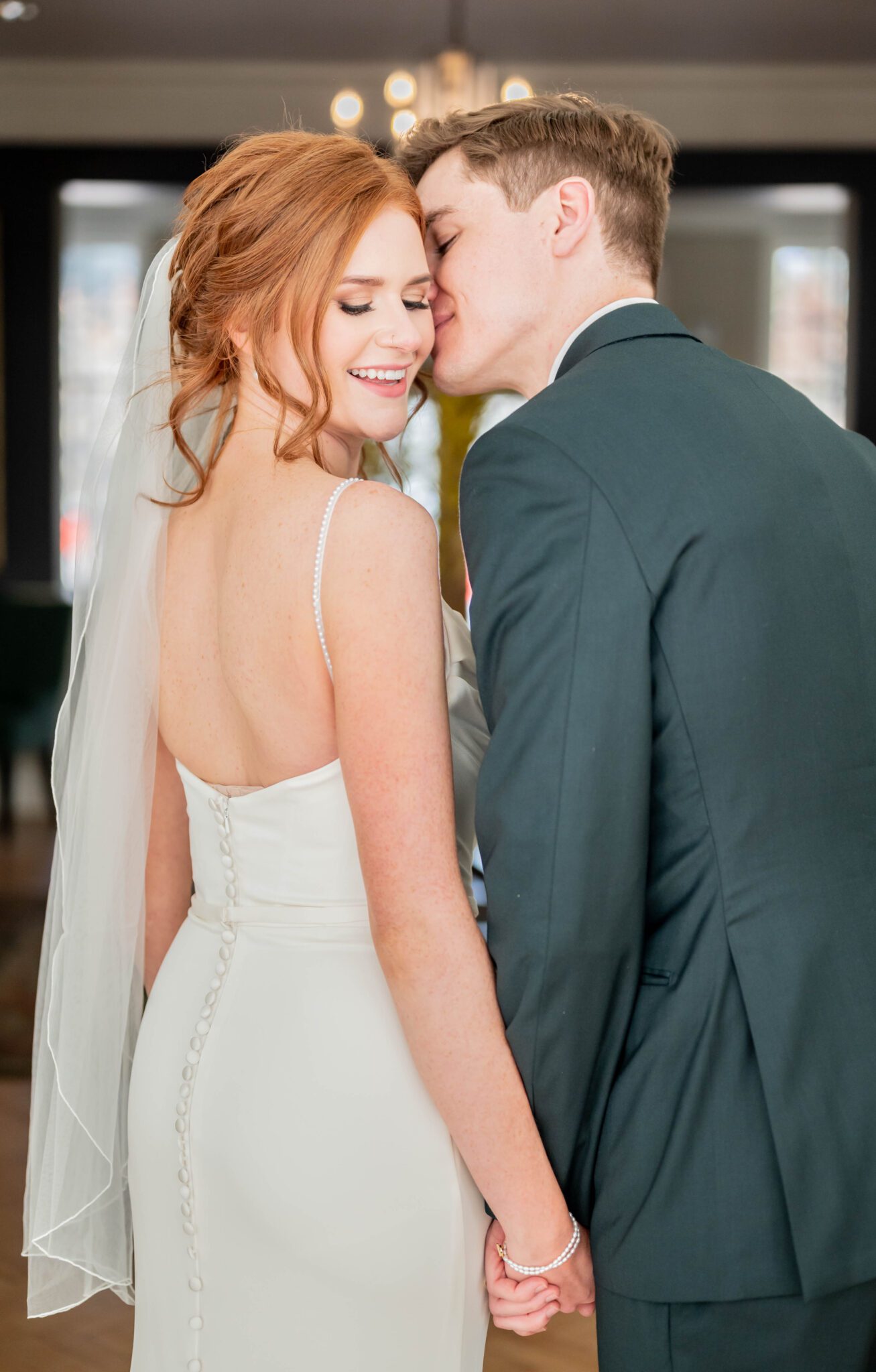 Couple portrait of groom leaning into bride, showing the back of bride's classic gown with button detailing, classic Calgary wedding inspiration.