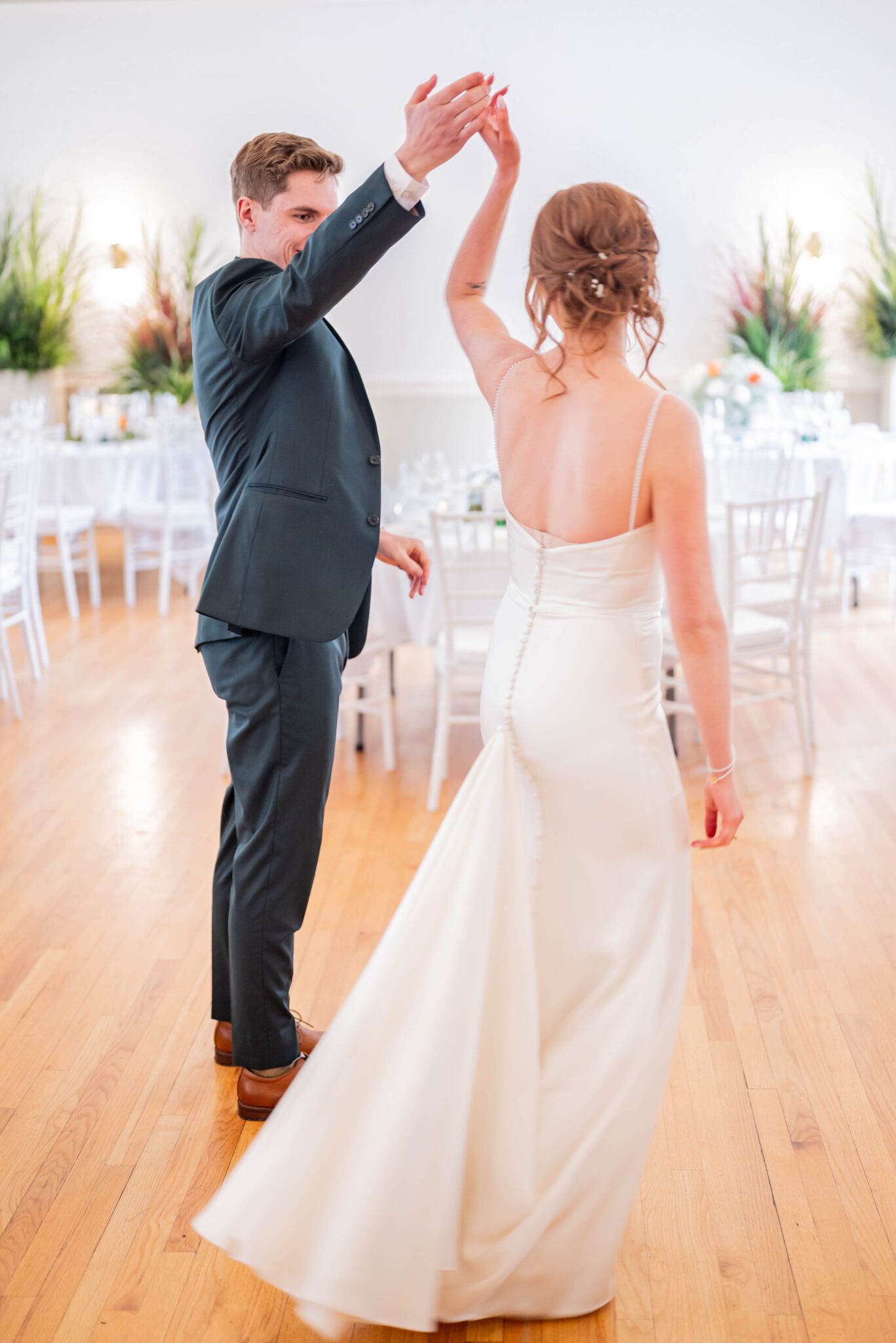 Groom twirls bride, while they enjoy a private first dance in their bright reception room at the Inn on Officer's Garden. 