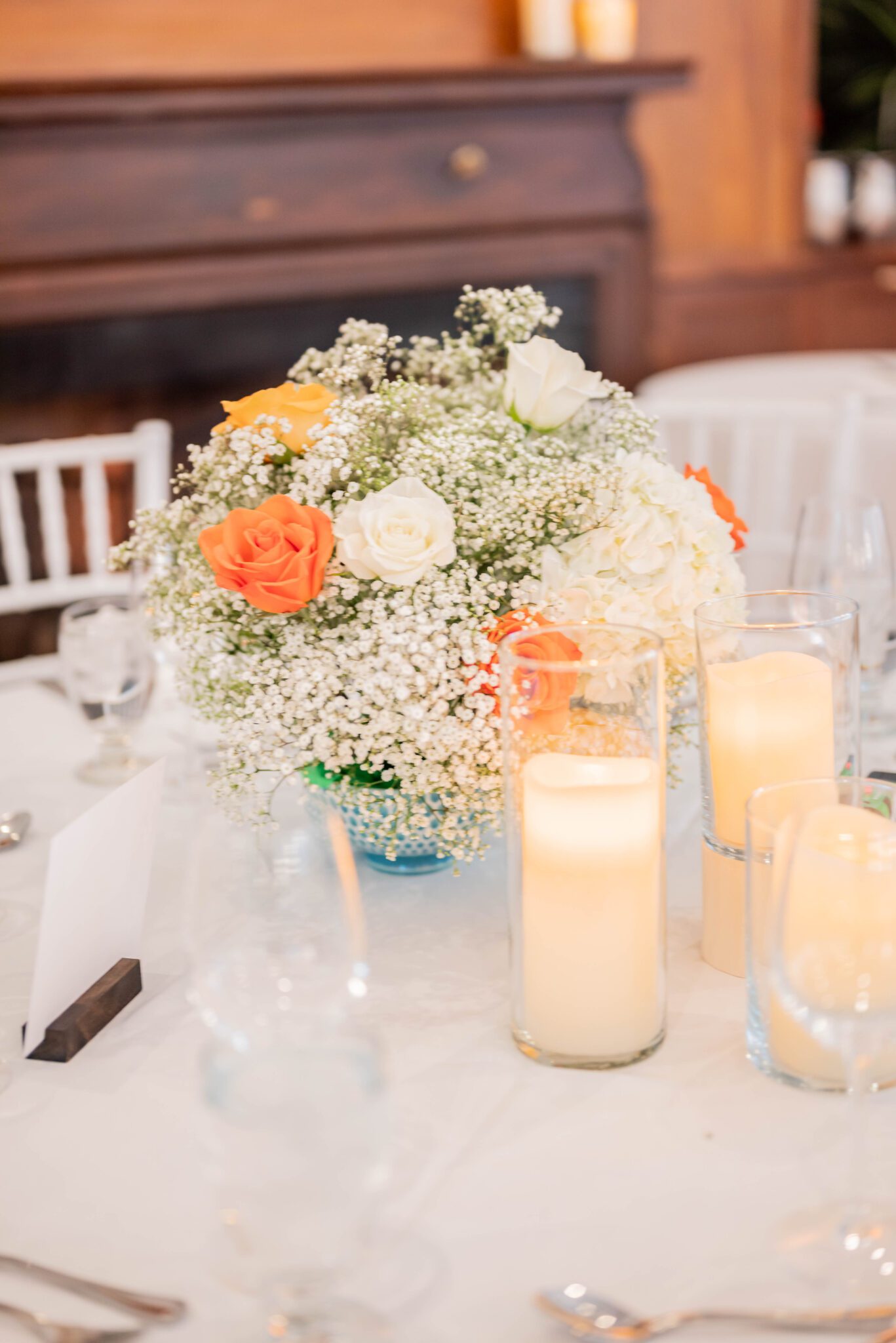 Close up photo of the reception tablescape with orange-infused floral arrangements with baby's breath and greenery, classic Calgary wedding inspiration. 